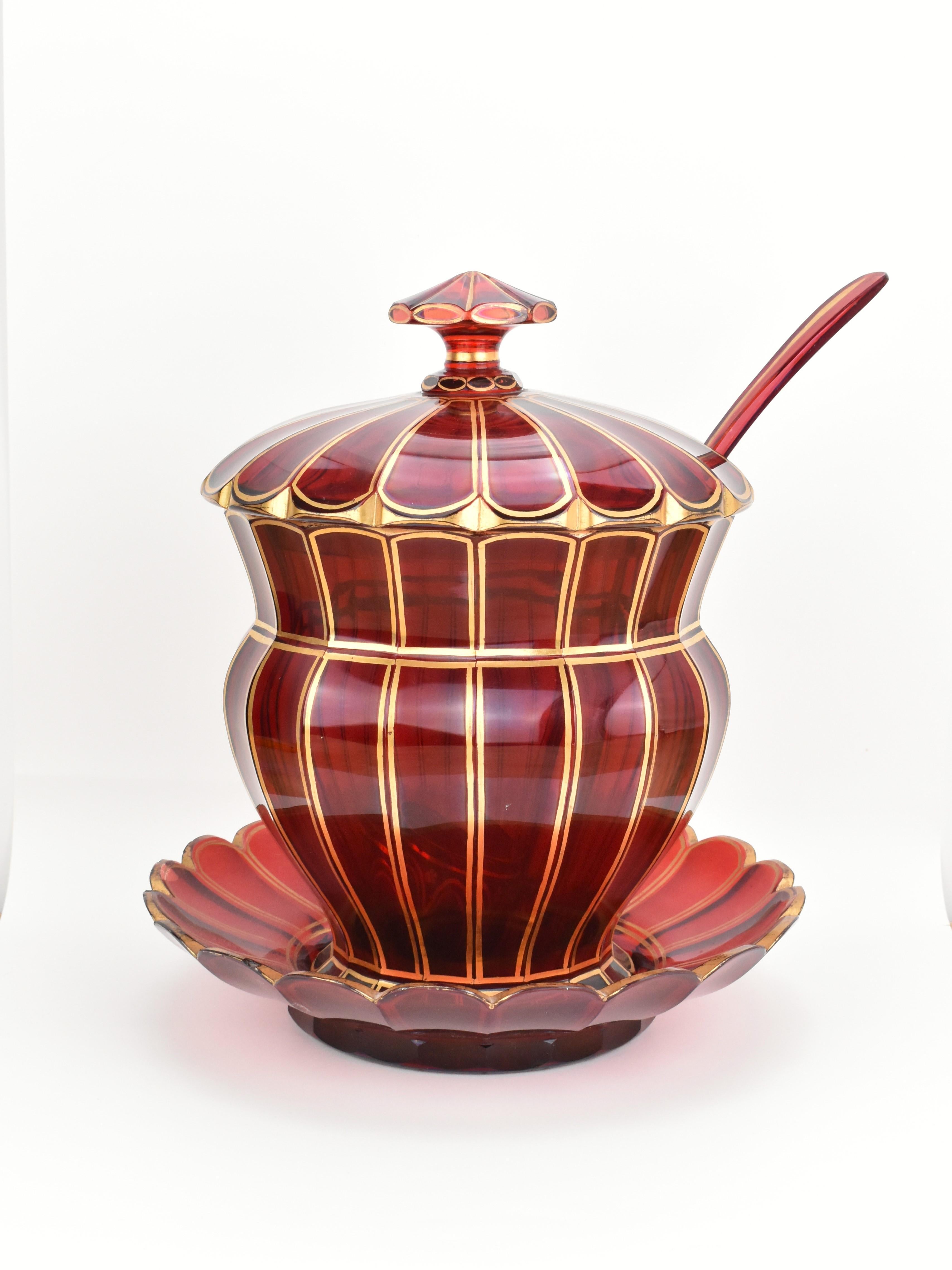 This exceptional large ruby red glass bowl set, complete with a matching lid, plate, and spoon, is a magnificent example of mid-19th-century Bohemian glass craftsmanship. Made from deep ruby red cut crystal glass, the set is richly adorned with