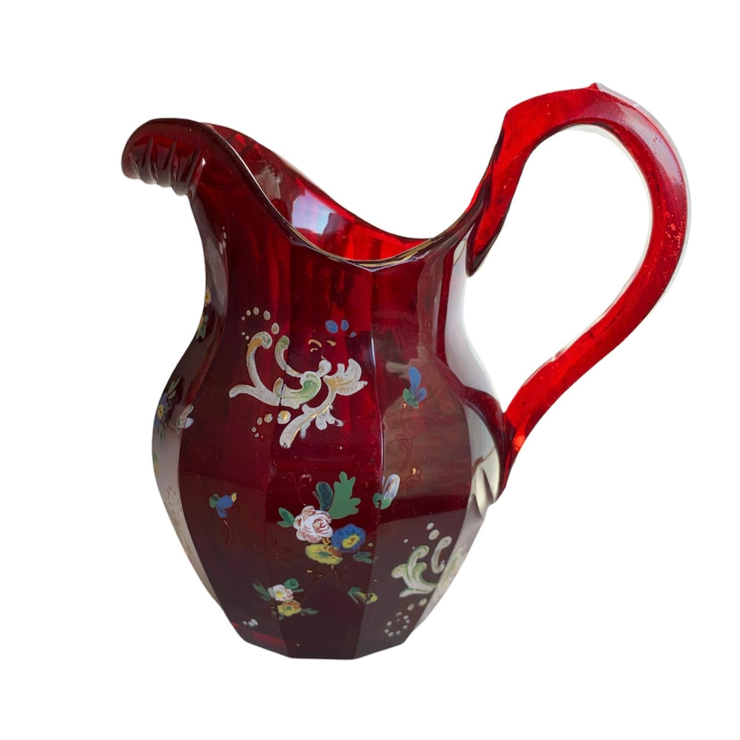 A beautifully shaped pitcher made of high quality ruby red glass with hand-painted enamel decoration, the 12 sided body features colorfull enameling with scrollworks and flowers, Bohemia, 19th century.
