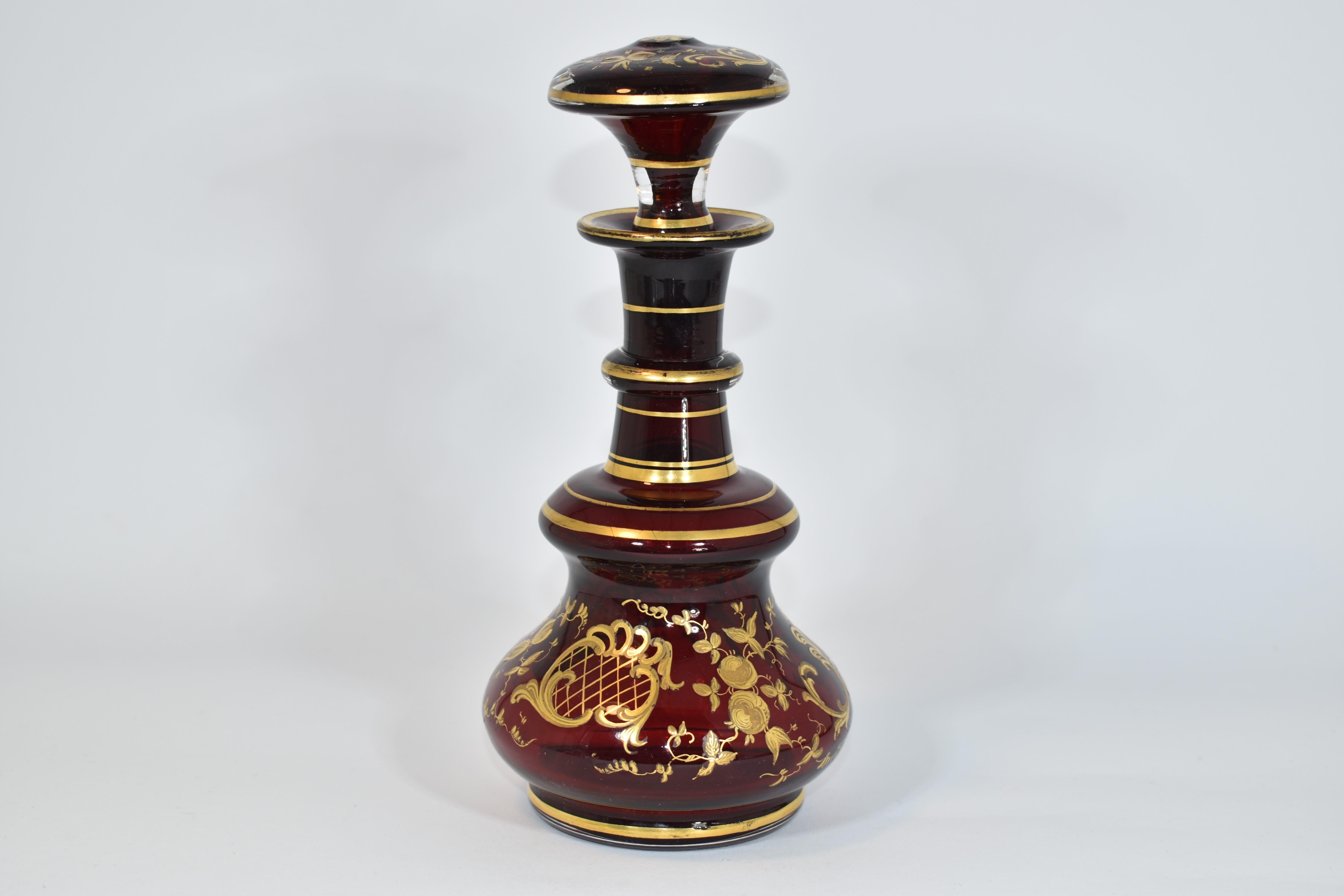 Atique perfume bottle (flacon) in ruby red blown glass, decorated all around with gilded enamel scrollworks and flowers
further gilding on the neck and stopper
Bohemia, 19th Century.