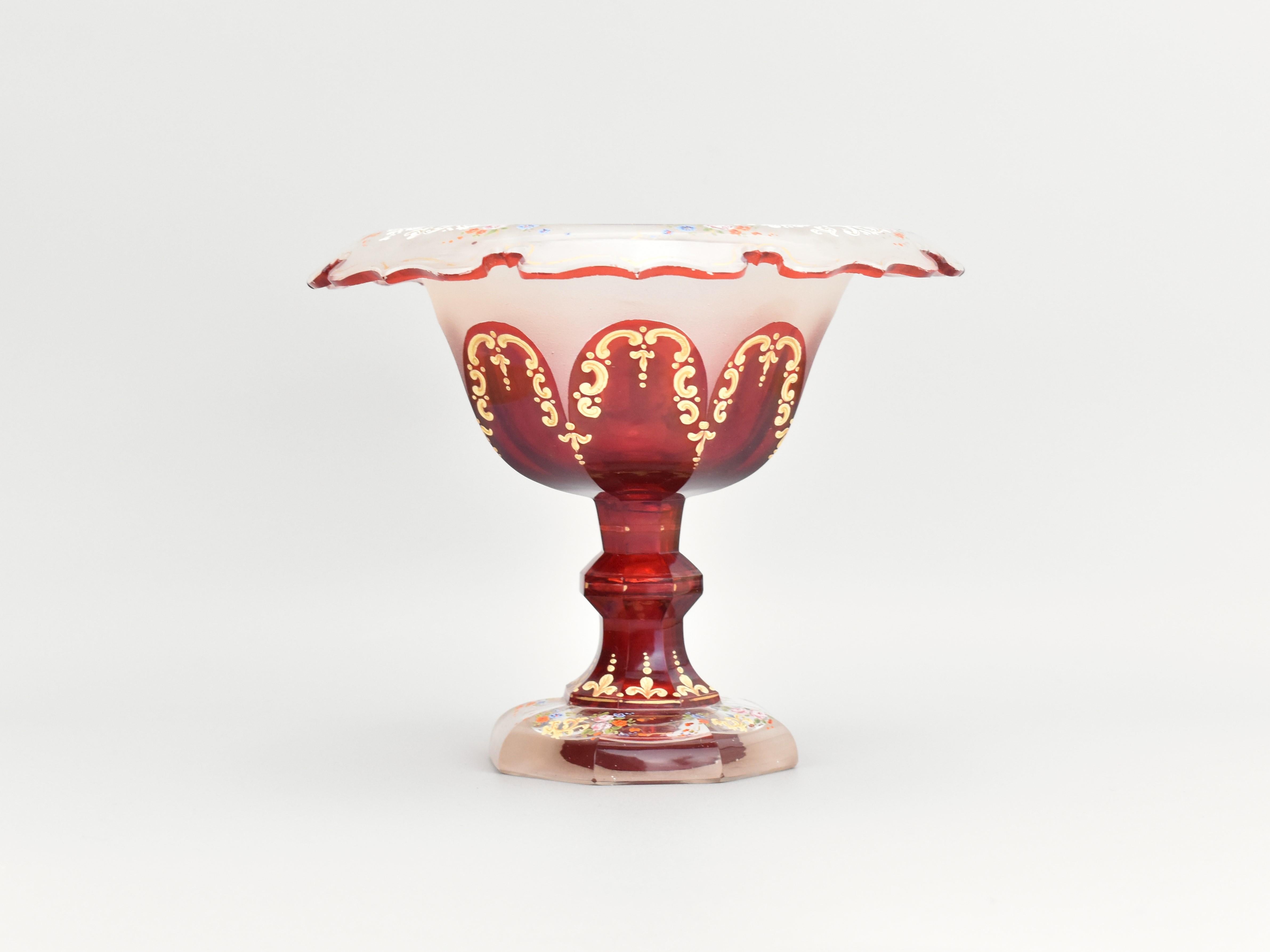 Este impresionante azucarero central, fabricado por Moser en el siglo XIX, ejemplifica el excepcional arte e innovación de los vidrieros bohemios. El cuenco presenta un llamativo diseño bicolor, que combina vidrio opaco y rojo rubí, creando un bello