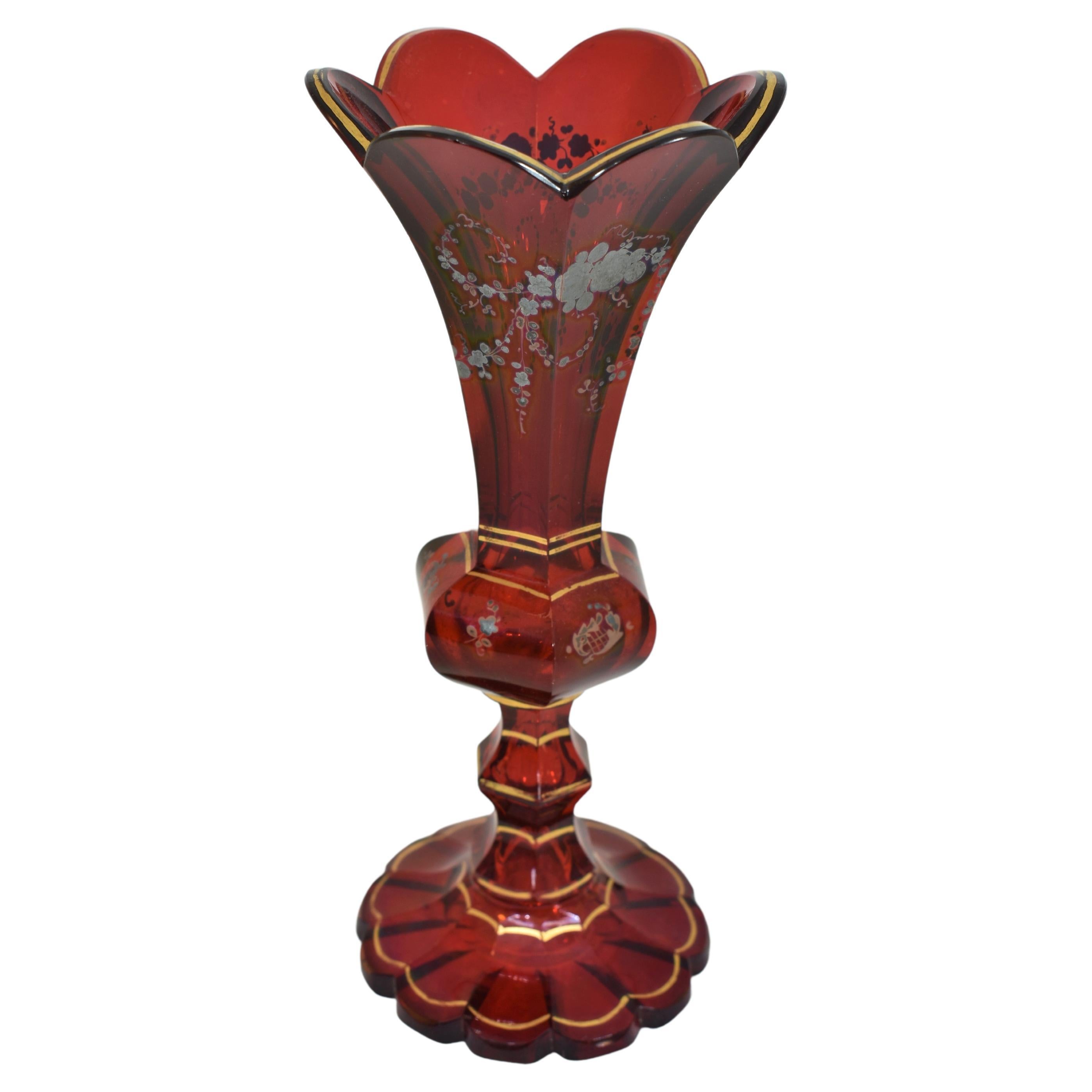 Elegant vase in ruby red glass profusely decorated with gilding and silver enameling decoration, with scalloped gilded rim, standing on a scalloped foot cut with a star pattern underneath.
Bohemia, 19th century
Stands 21 cm high.