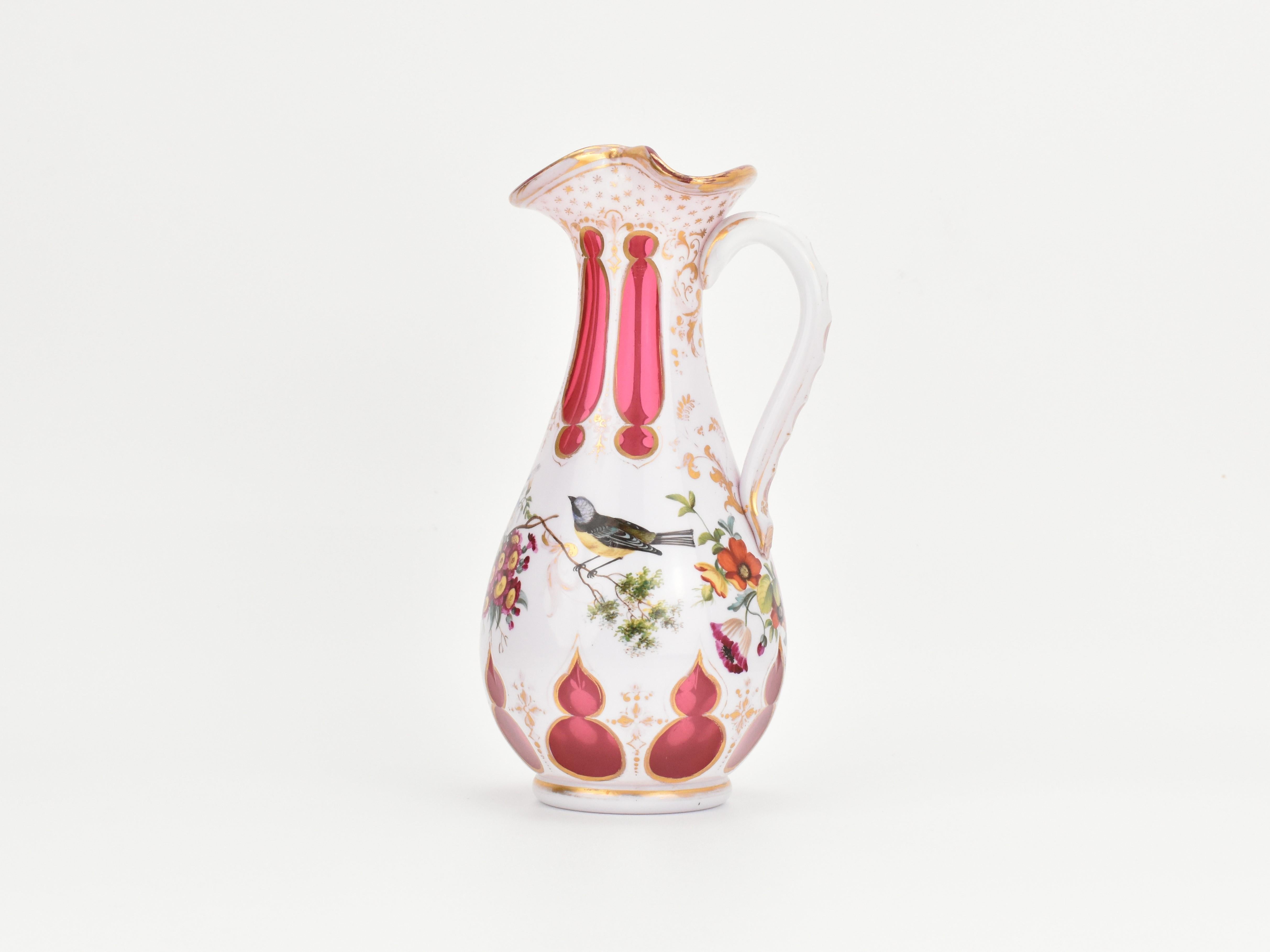 Esta antigua jarra de Bohemia, fabricada en vidrio opalino de color arándano y fechada a mediados del siglo XIX, es un impresionante ejemplo del arte del vidrio bohemio de la época. La jarra está hecha de vidrio bicapa, con una rica base de vidrio