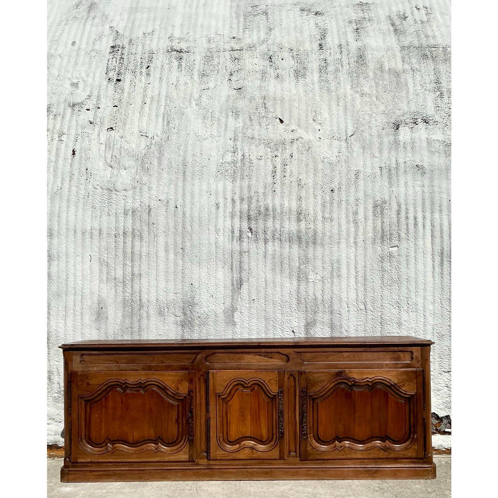Embodying the grandeur of Old World craftsmanship, this 19th-century carved credenza brings French Provincial elegance to modern interiors. Handcrafted from richly grained hardwood, this stately piece showcases exquisite panel detailing, serpentine