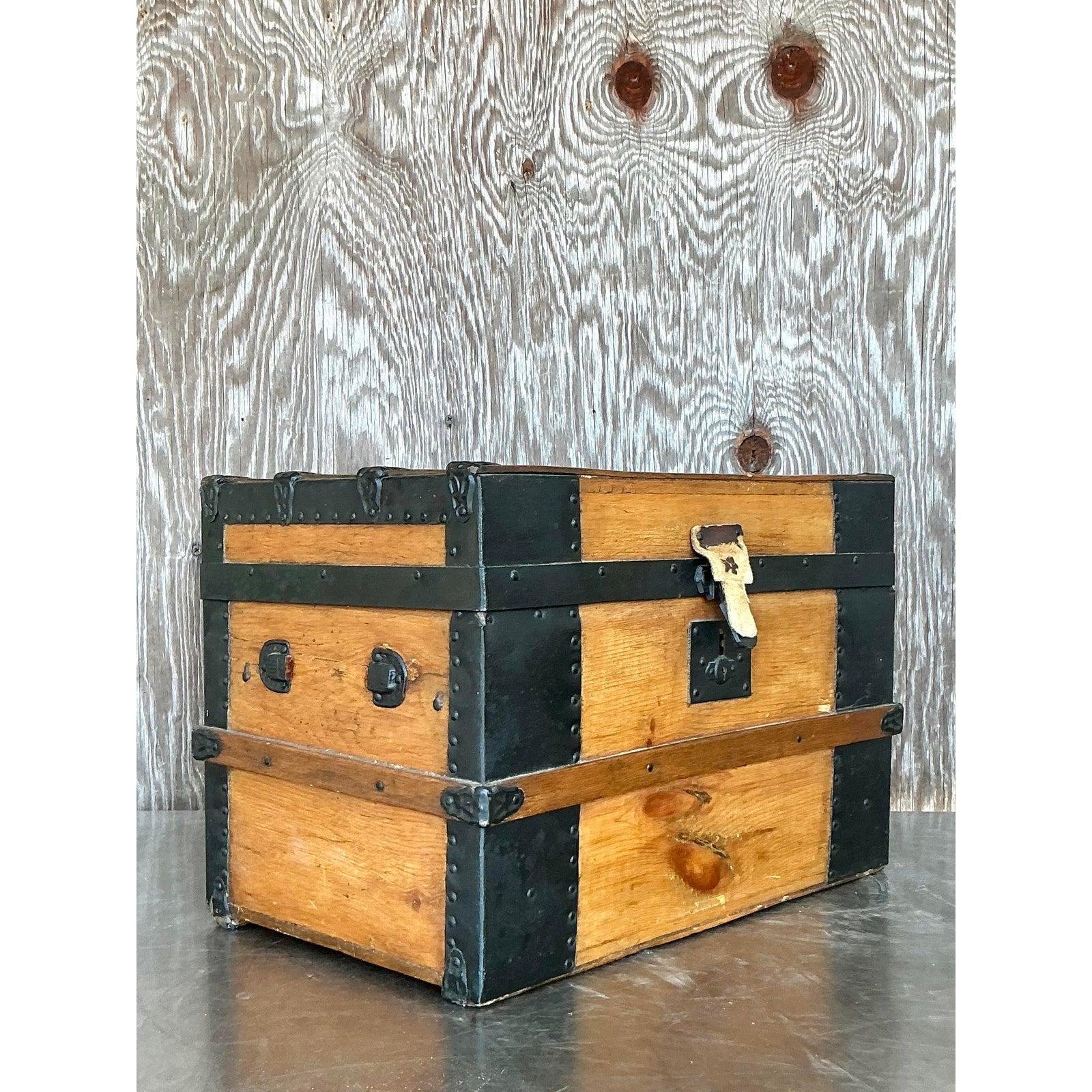 Remontez le temps avec cette exquise malle de voyage vintage du XIXe siècle, véritable relique de l'aventure et de l'artisanat. Construite en bois massif avec des bords renforcés en fer, cette pièce dégage un charme rustique tout en offrant à la