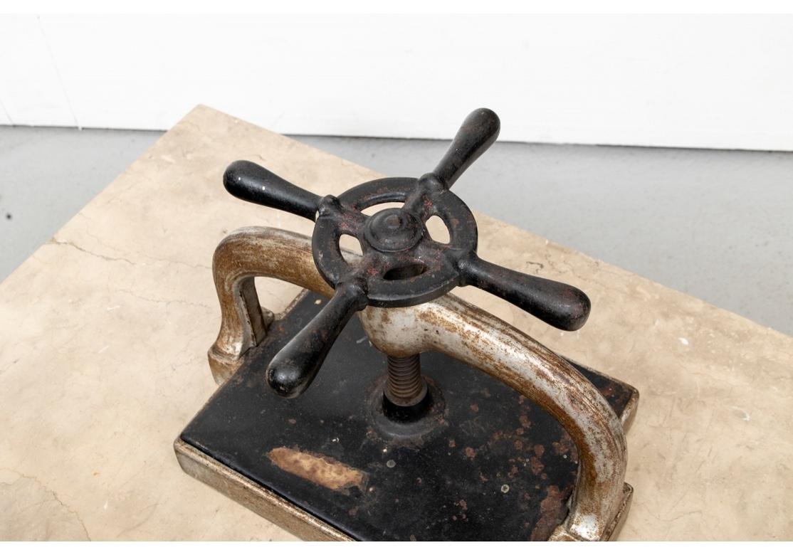A working antique iron book press which sits atop a four drawer art storage cabinet with two brass identification card holders on each drawer. Three of the drawers have their original dividers. The Cabinet has a Tan Striated Stone top. 
The Art