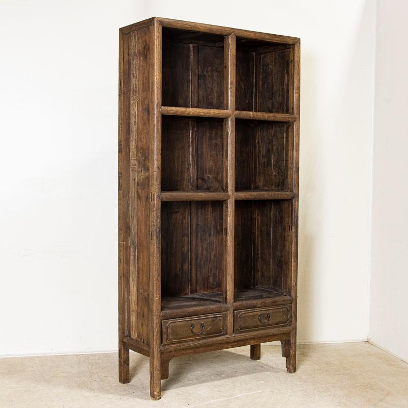 Great architectural lines define this open style bookcase. The raw, rather organic finish of the natural wood compliments the simple lines which make it an outstanding display cabinet as well. Two drawers create balance at the base. Any knicks, old
