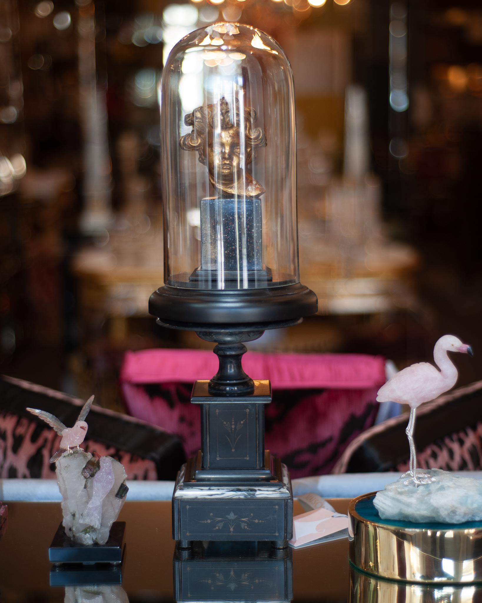 An antique Borghese Putti Cherub, under a glass cloche, mounted on a handmade marble pedestal base.