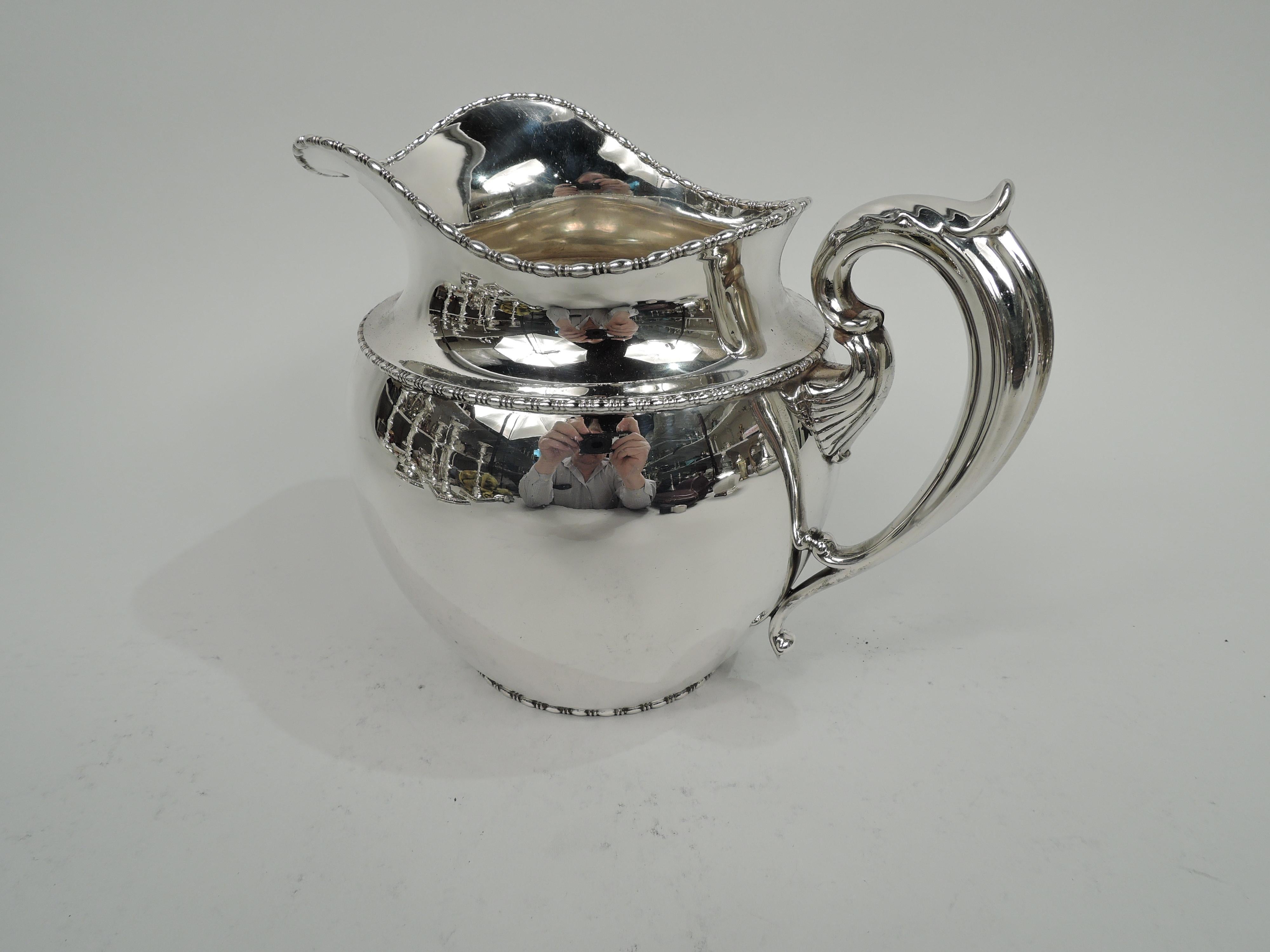 Edwardian Classical sterling silver water pitcher, circa 1910. Wide ovoid body with helmet mouth and leaf-capped scroll handle with split bottom mount. Bead-and-reel rims. Fully marked including no. 25 and marks for Boston firms Bigelow, Kennard and