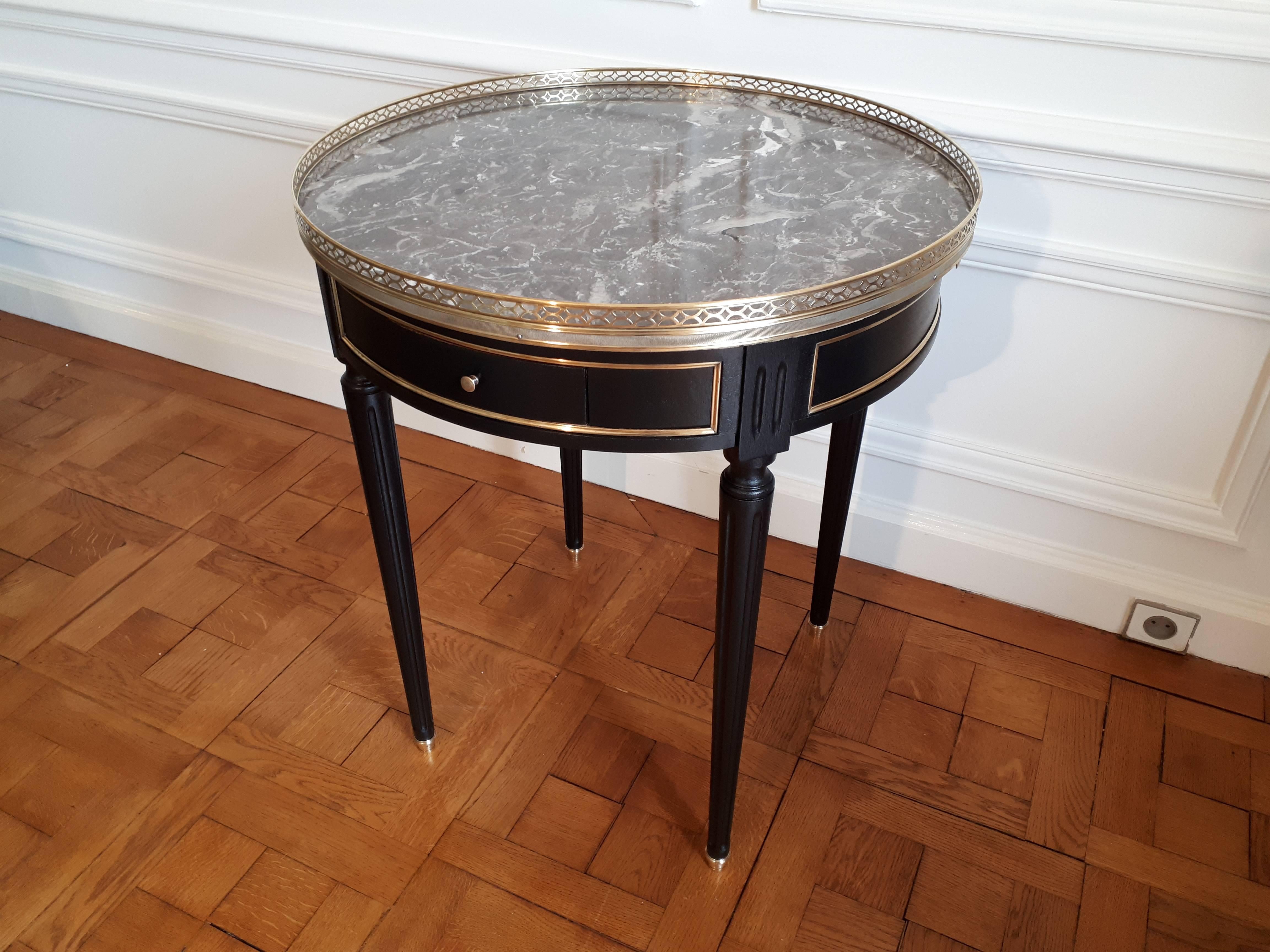 French Louis XVI style bouillotte table with a grey marble-top.
Brass gallery and fluted legs finished with golden bronze clogs.
The whole belt is also decorated with golden brass.
The table has two dove-tailed drawers and two pull-out tablet