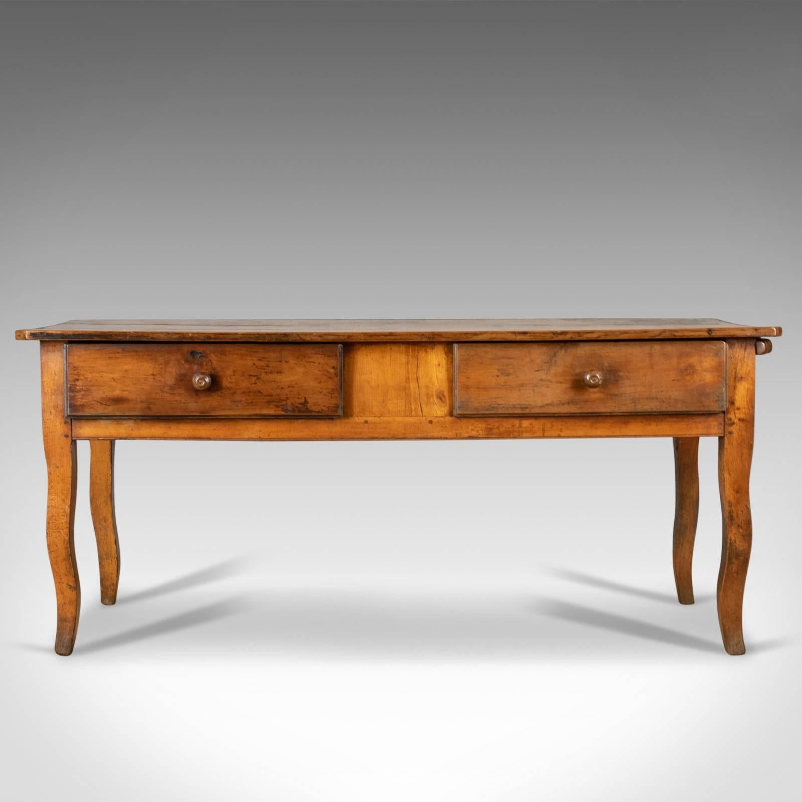 This is an antique boulangerie table, a French, country kitchen, bakery table in fruitwood dating to the early 19th century, circa 1800.

Highly attractive color and patina to the fruitwood
Grain interest to the broad planked top
Featuring