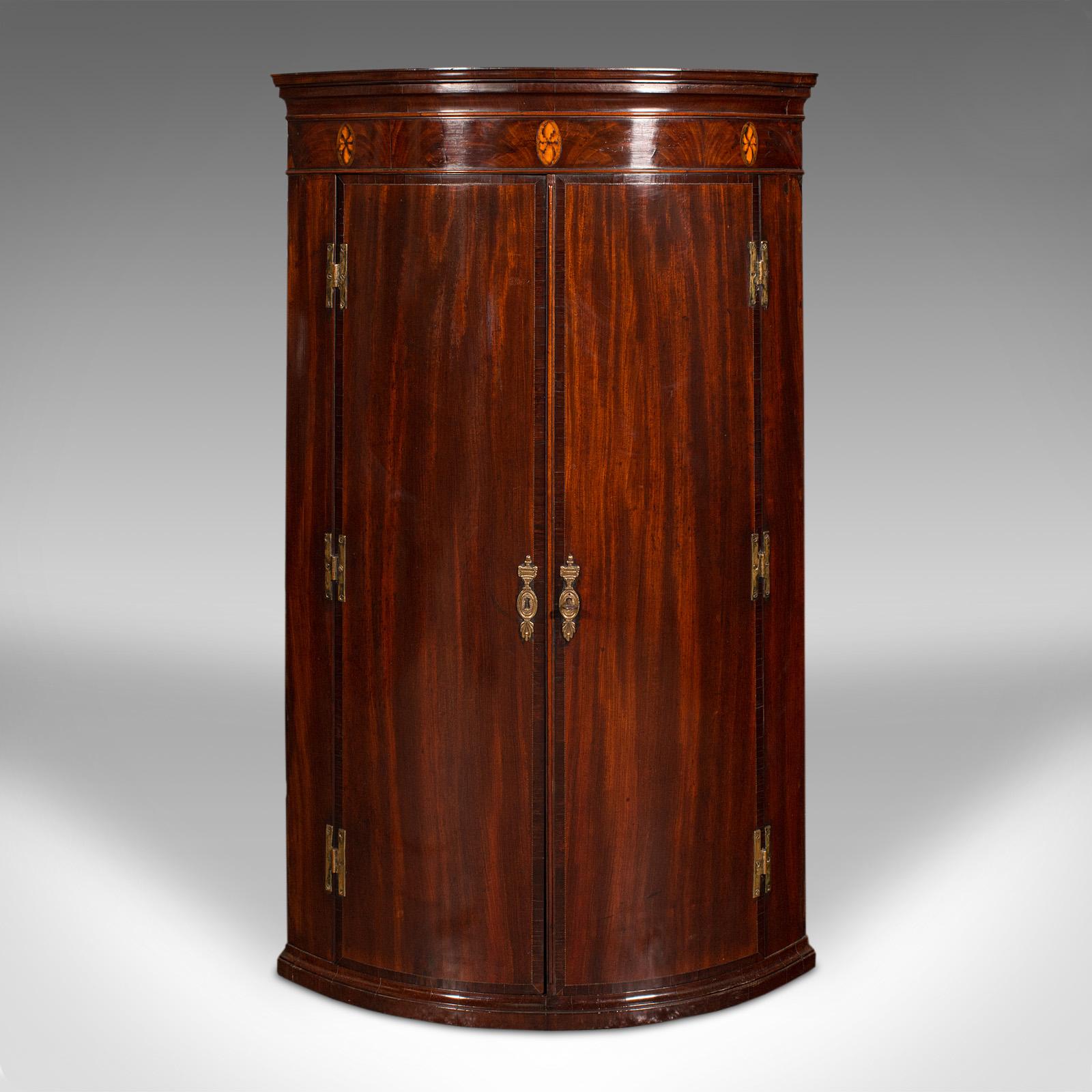 This is an antique bow front corner cabinet. An English, flame mahogany and oak wall cupboard, dating to the Georgian period, circa 1780.

Exquisite craftsmanship sets apart this superb cabinet from George III's reign
Displays a desirable aged