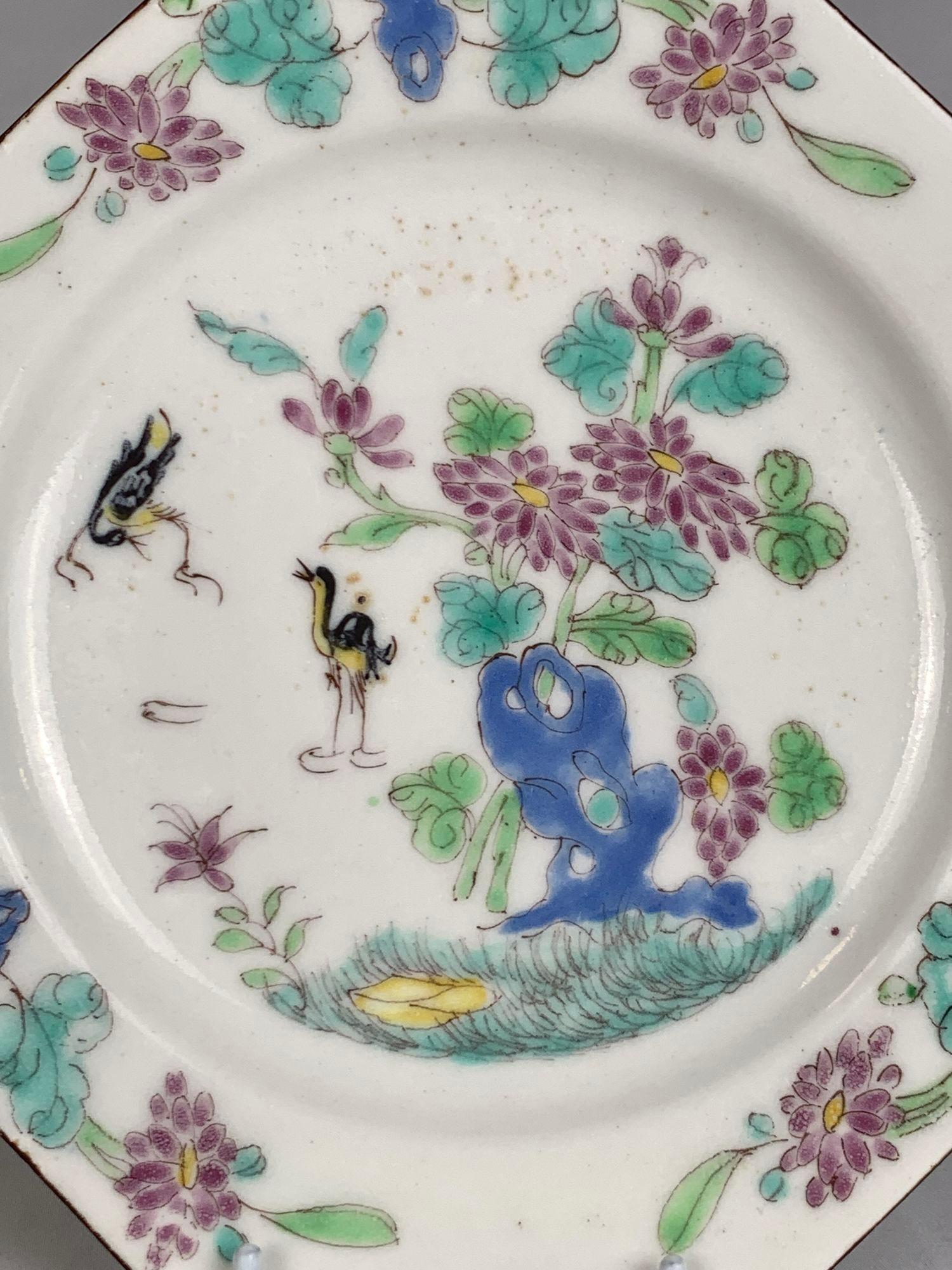 Cette assiette en porcelaine Bow du milieu du XVIIIe siècle présente une scène de chinoiserie peinte à la main avec un couple de cigognes noires.
L'une des cigognes patauge dans l'eau tandis que l'autre vole au-dessus.
Près des cigognes, le