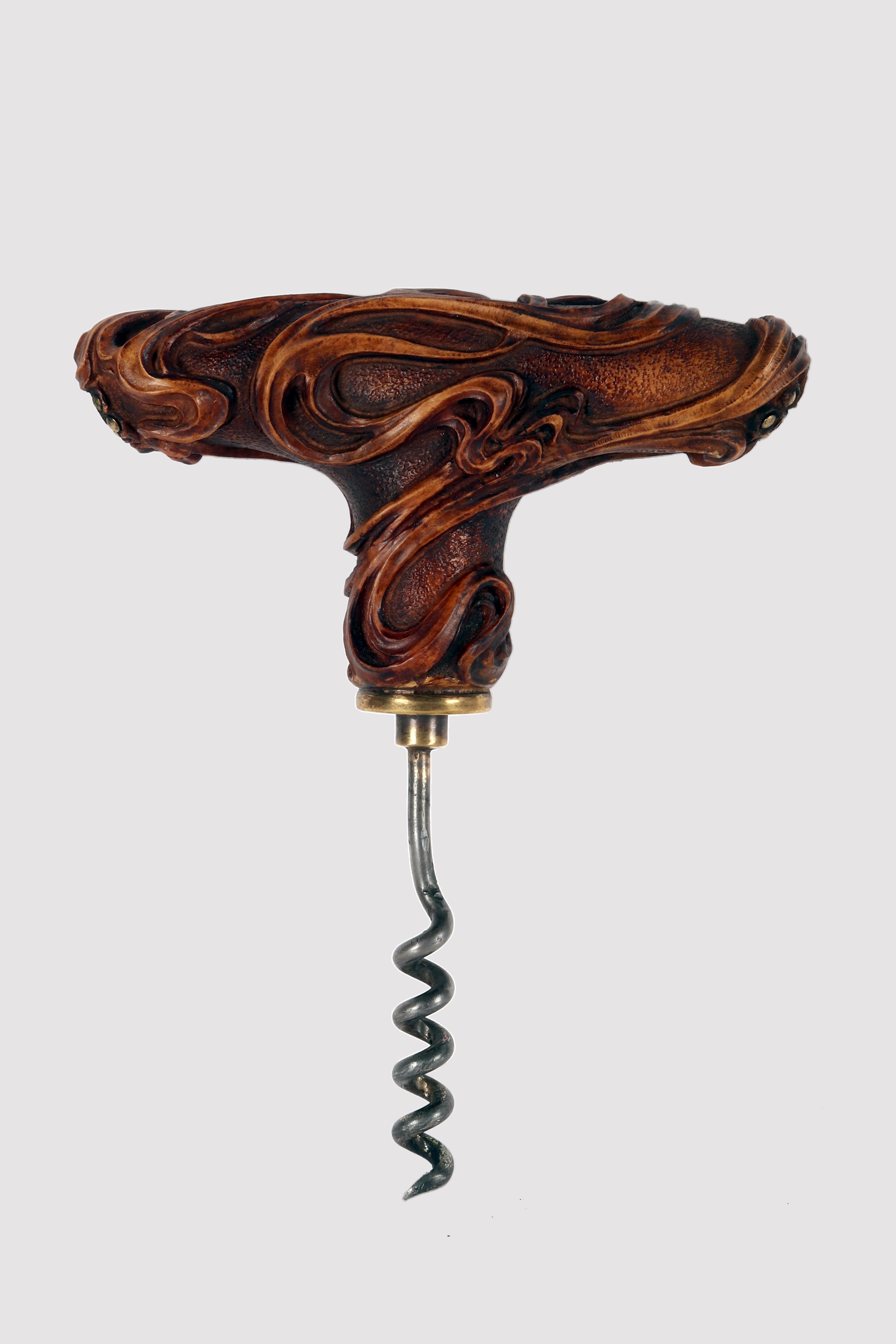 Antique Art Nouveau corkscrew made of hand carved boxwood, depicting plant branches enveloping the knob with brass flowers at either end of the T. The corkscrew worm is made of iron with a brass attachment base. The screw is known as a worm design