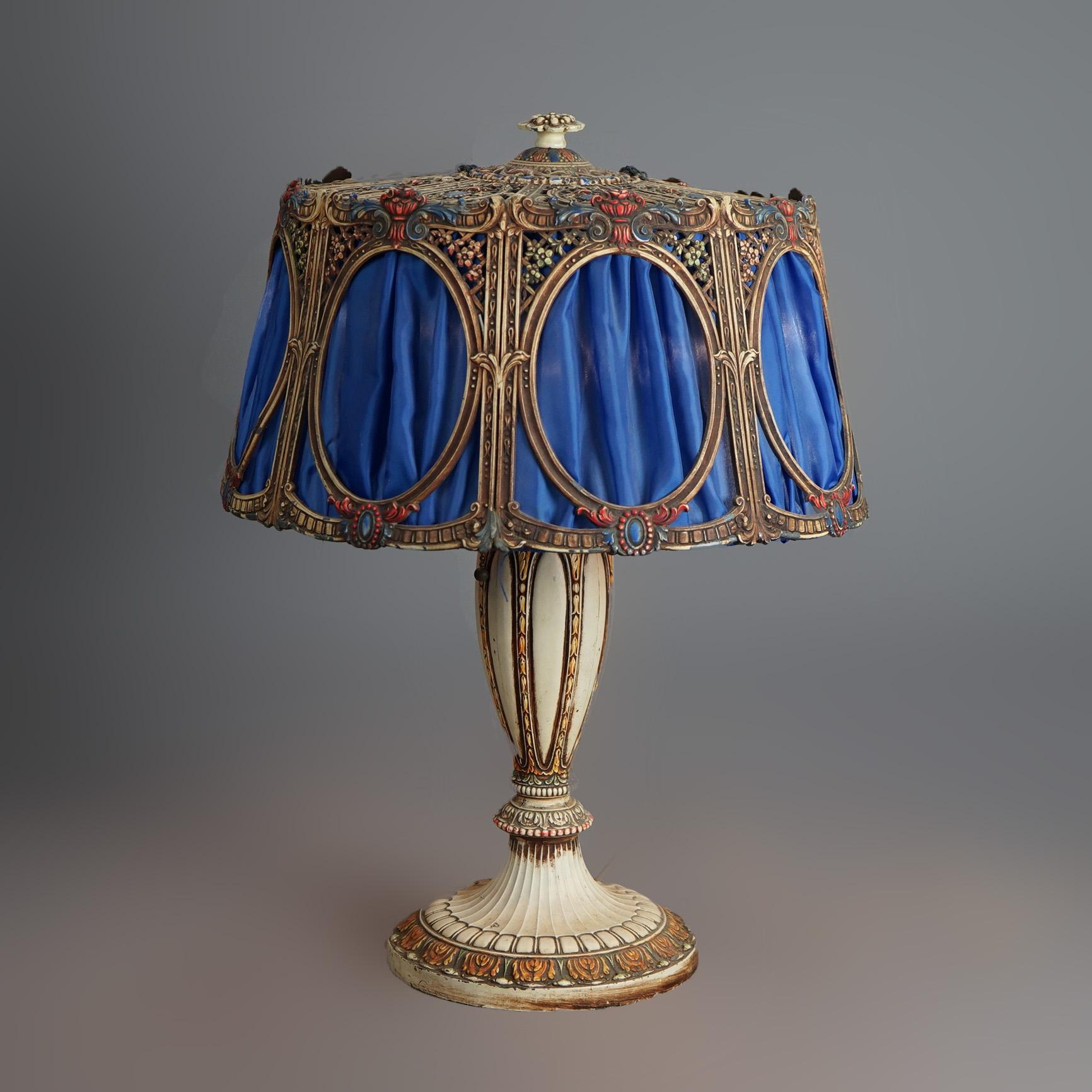An antique Arts & Crafts table lamp by Bradley and Hubbard offers polychromed cast metal shade with fabric over double socket matching base, c1925

Measures- 22''H x 16.5''W x 16.5''D

Catalogue Note: Ask about DISCOUNTED DELIVERY RATES available to