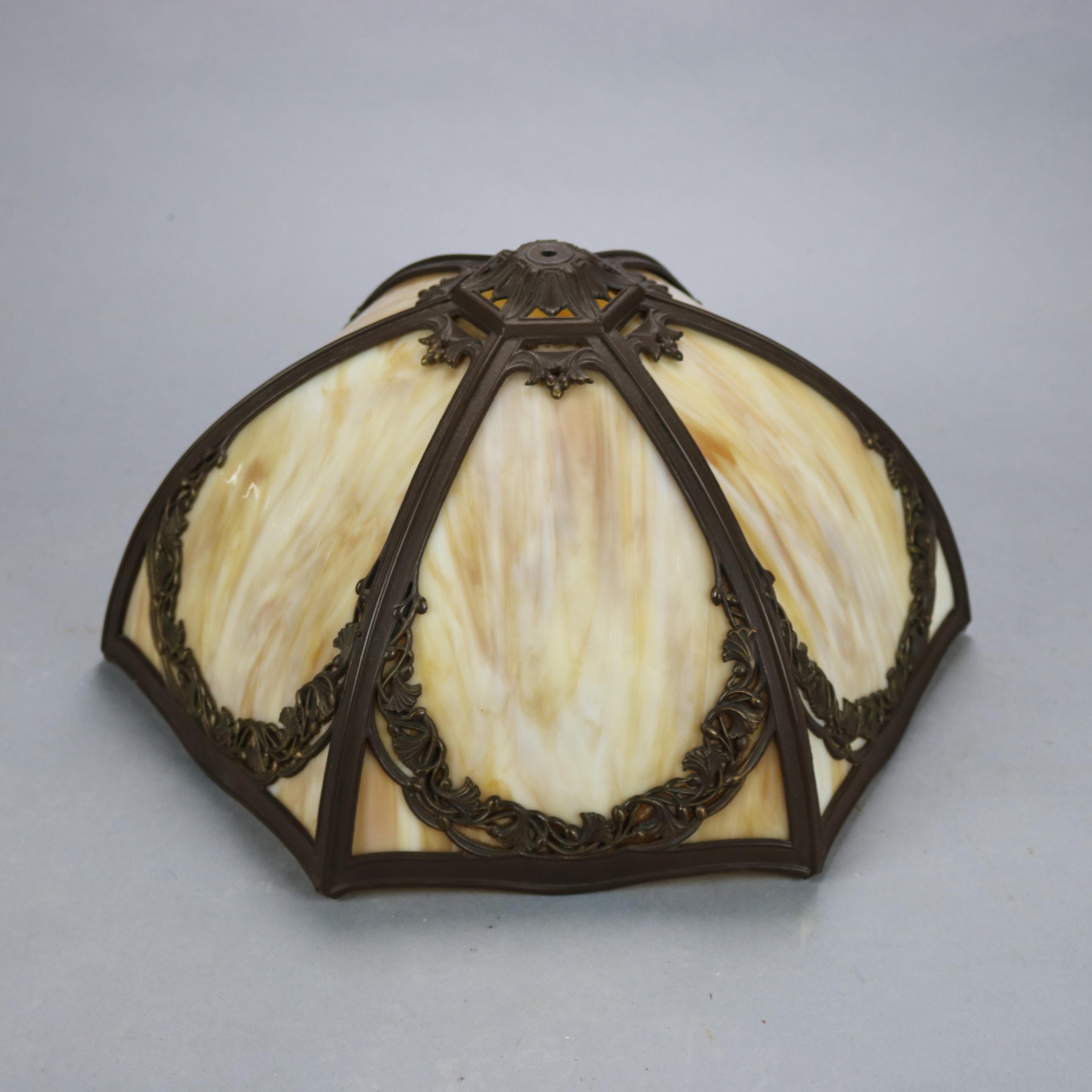 An antique Arts & Crafts table lamp by Bradley and Hubbard offers cast floral shade housing bent slag glass panels over double socket base, maker signed, c1920 

Measures: 21.25