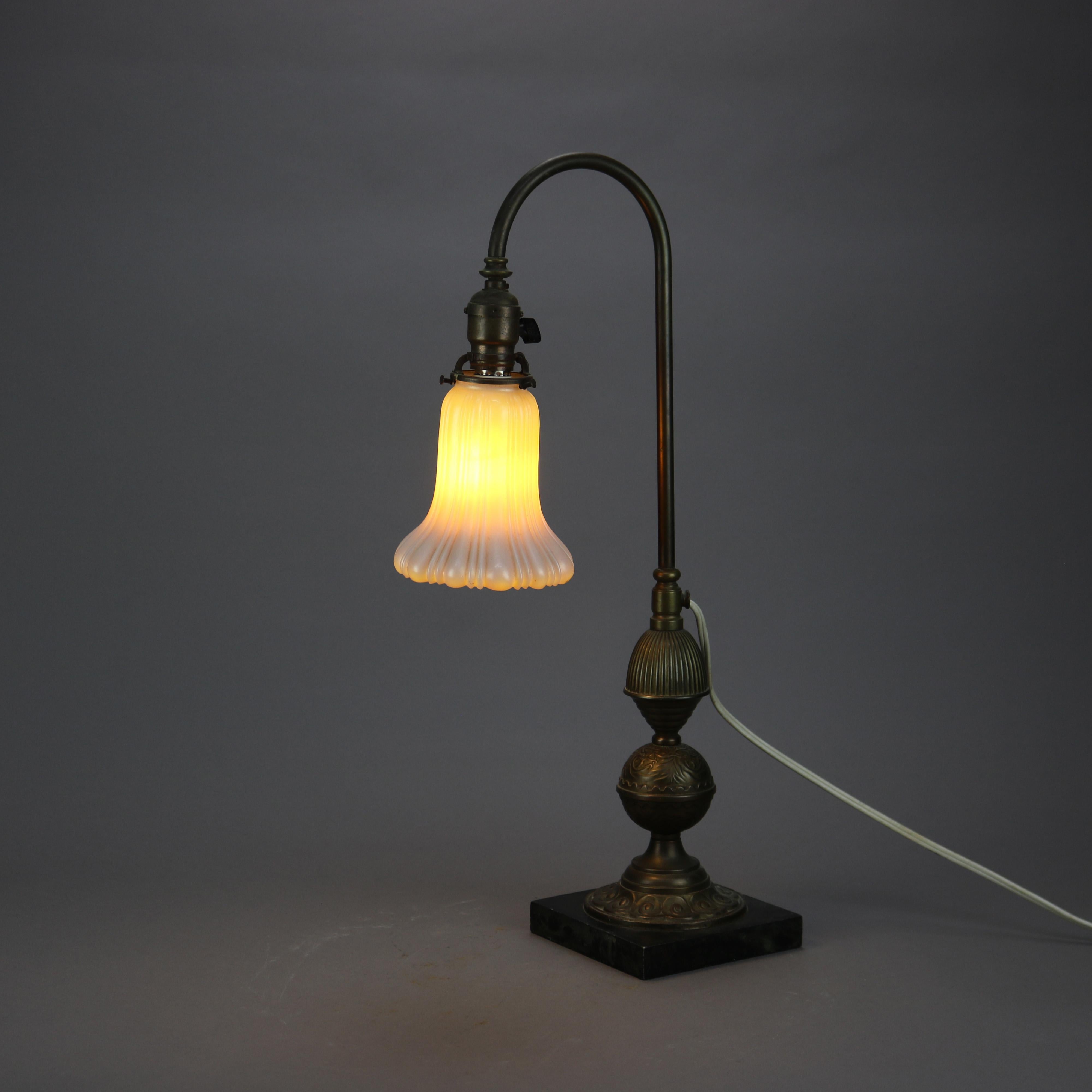 An antique Arts & Crafts desk lamp in the manner of Bradley and Hubbard offers gooseneck form with embossed scroll base on marble plinth, calcite ribbed shade, c1910

Measures - 24''H X 6''W X 12''D.

Catalogue Note: Ask about DISCOUNTED DELIVERY