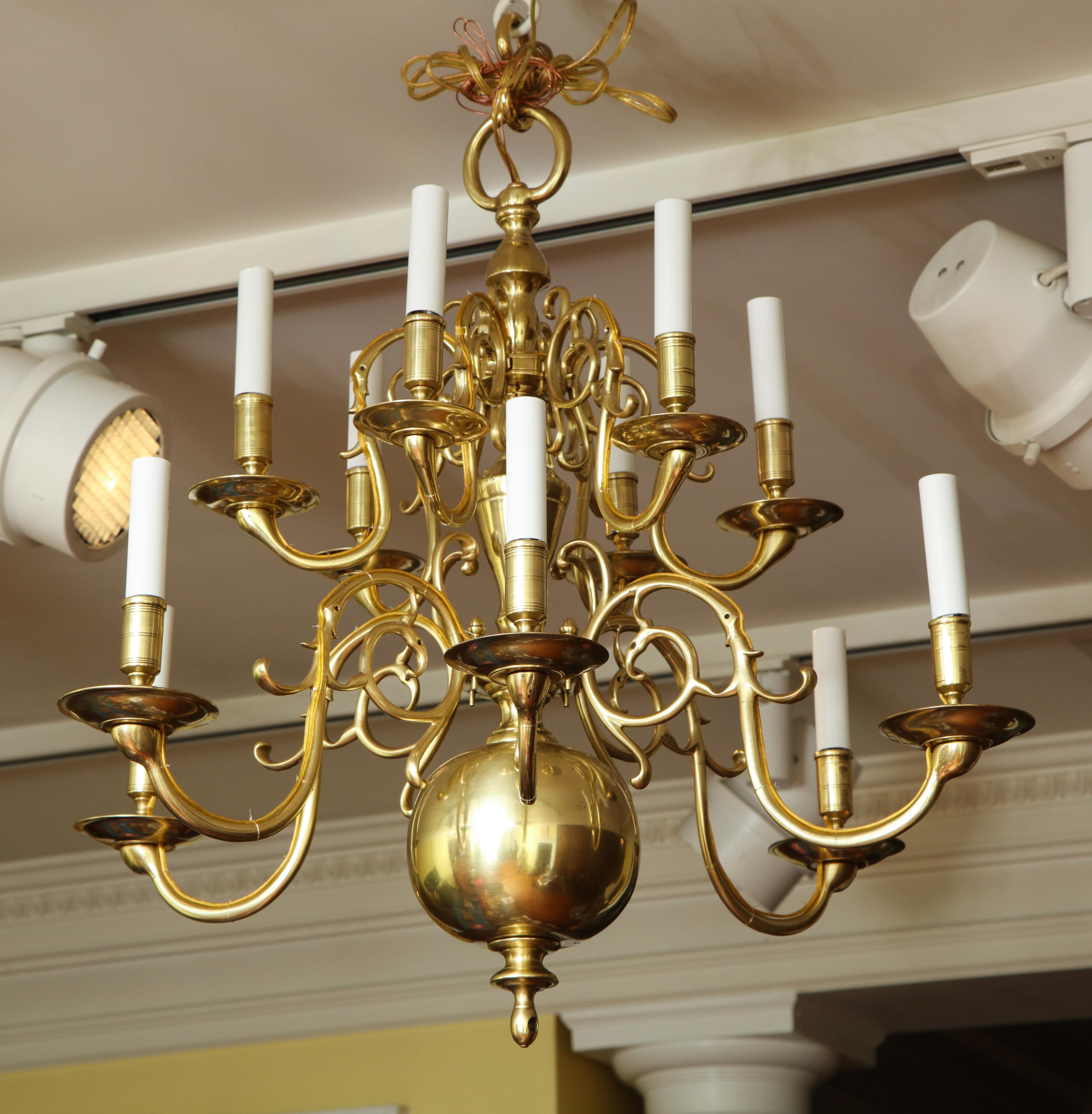 Fine antique brass 12 light chandelier, having two tiers of pierced and scrolling arms ending in plain cups and turned bobeches, having a turned sectioned shaft with a large lower ball and turned finial with brass ring. European mid-19th