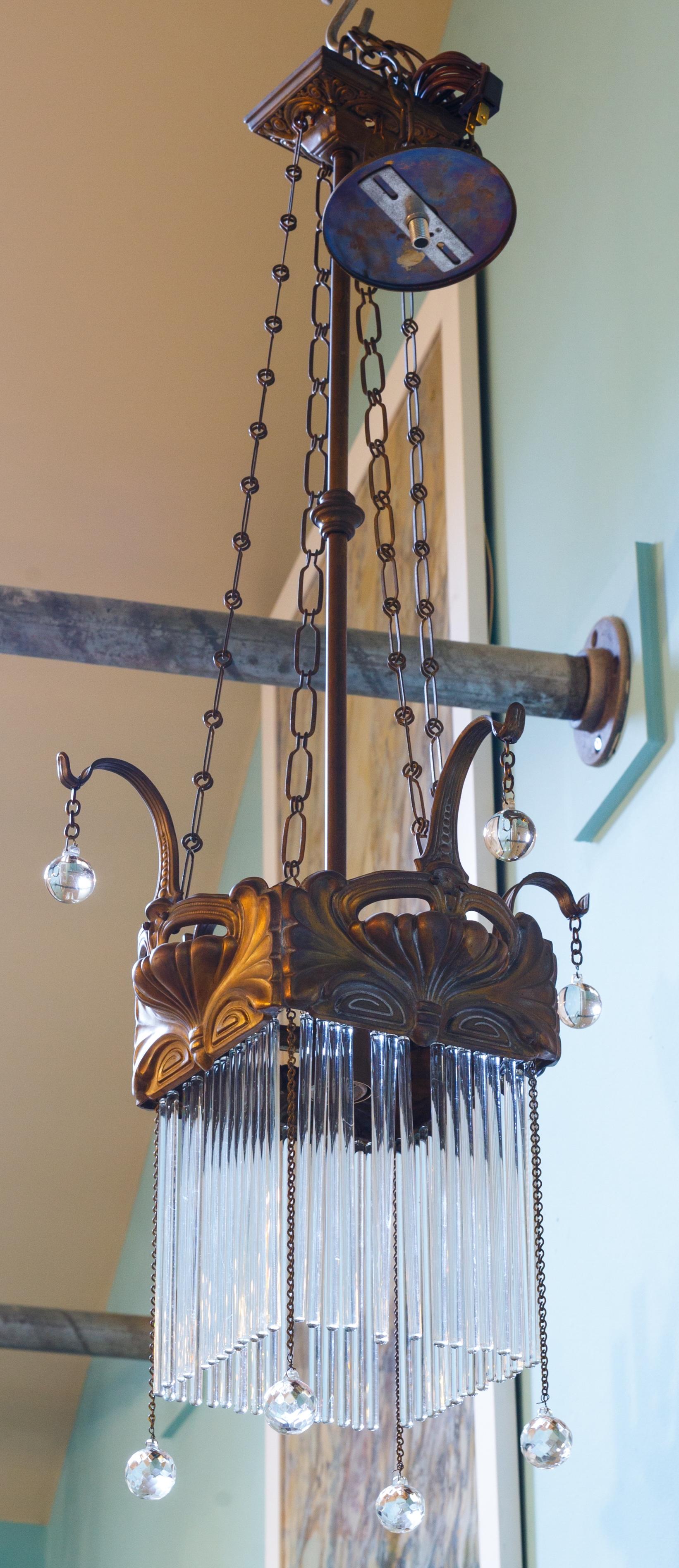 This charming art nouveau chandelier is one of the few art nouvea pendants we have encountered that is square. A unique take on the epochal style. Wonderfully crafted hand-hammered repousse brass  with all original crystals. The light has all its