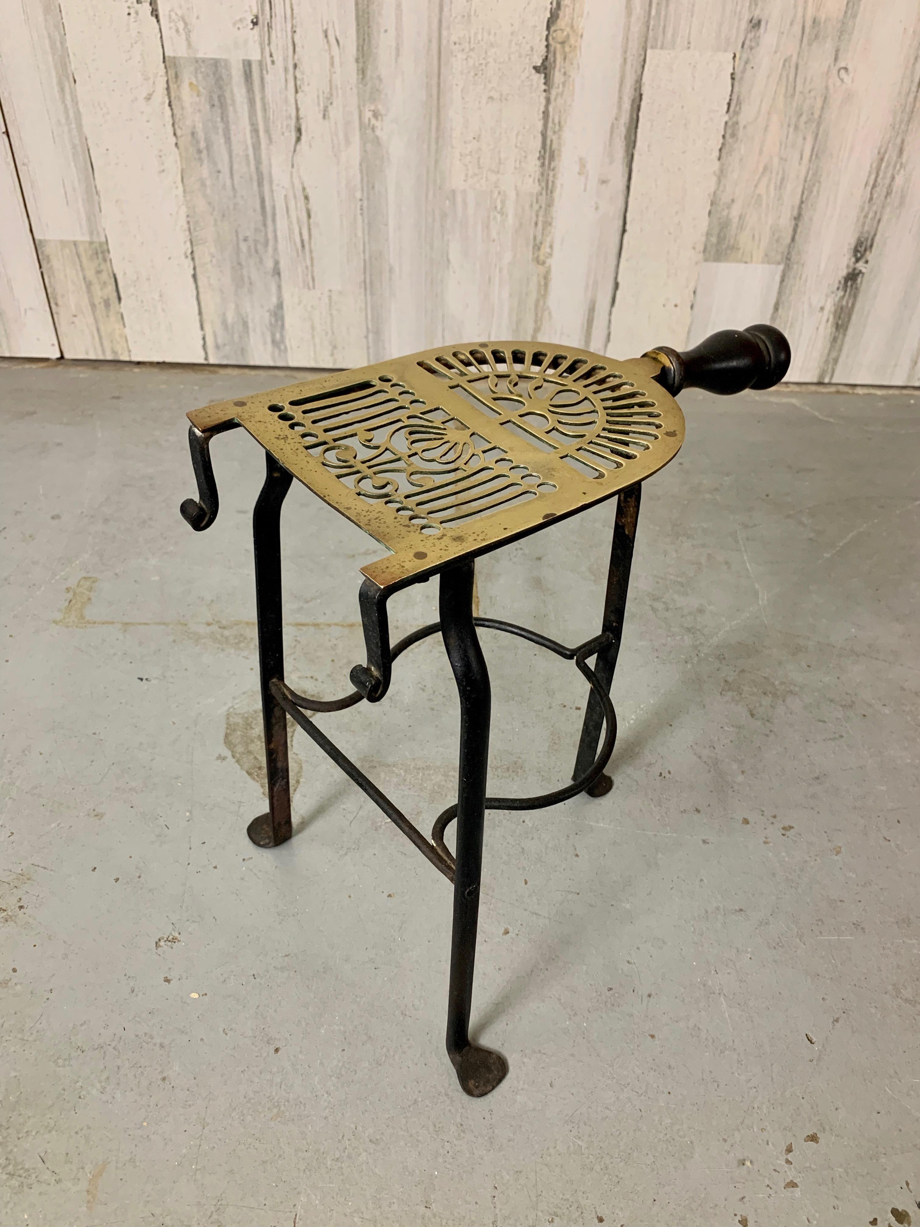 Hand cut brass plate mounted on hand forged iron tripod base with turned-wooden handle. Great fireplace accent or plant stand.