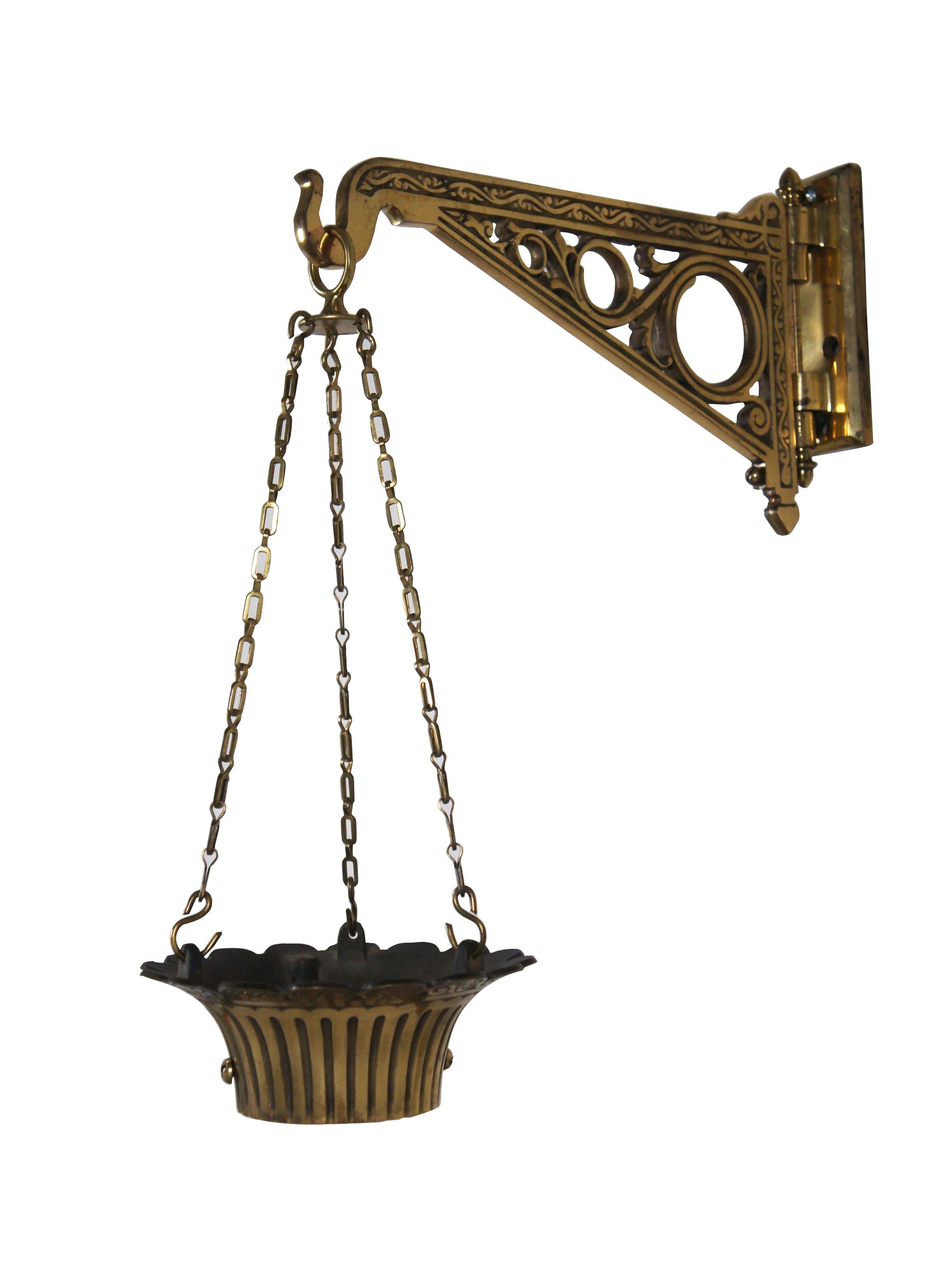 Late 19th - early 20th century solid brass, articulated / rotating wall bracket, chains, and collar for a pharmacist's / apothecary show globe. Bracket features etched and pierced swirling foliate designs and acorn shaped finials on the hinge. Hinge