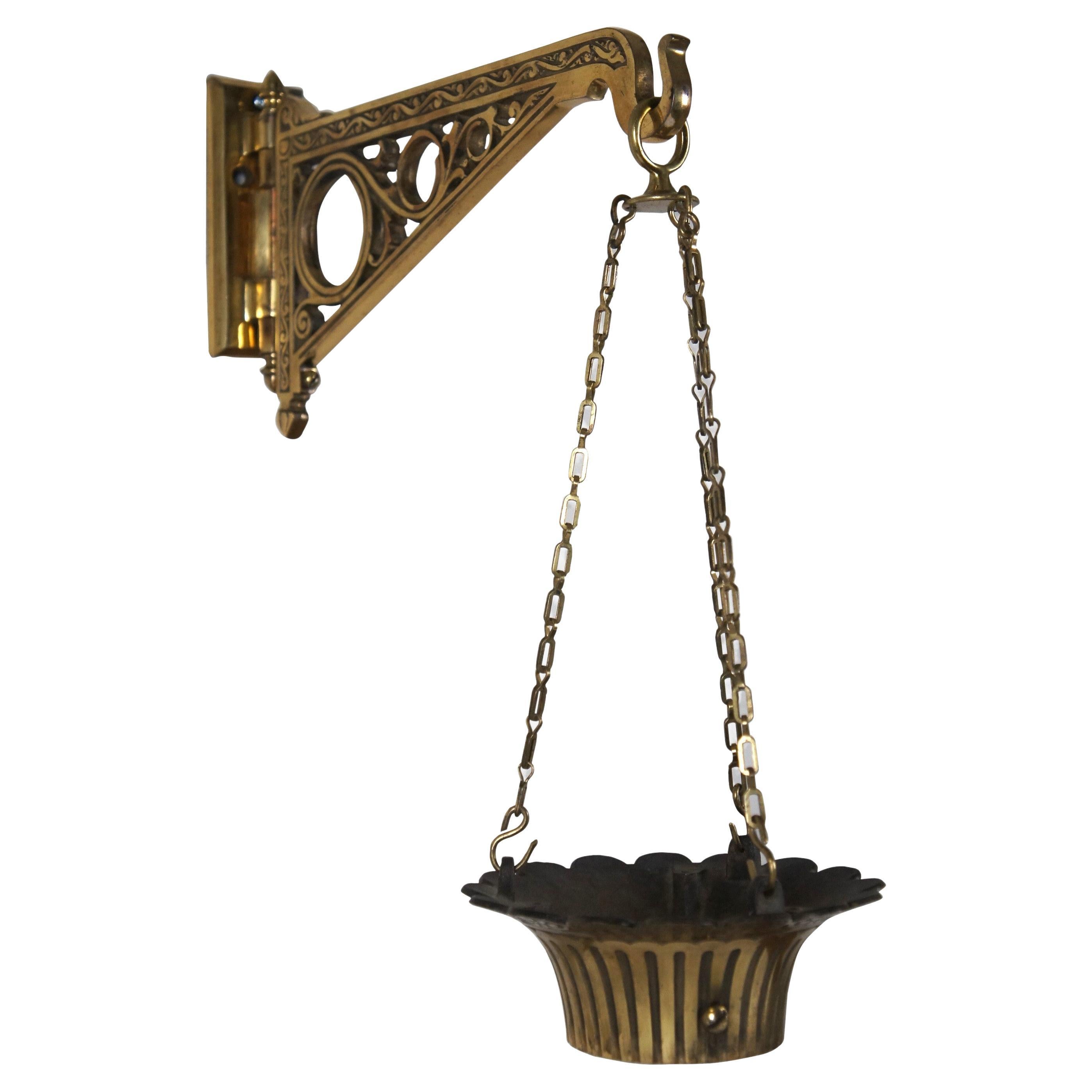 Late 19th - early 20th century solid brass, articulated / rotating wall bracket, chains, and collar for a pharmacist's / apothecary show globe. Bracket features etched and pierced swirling foliate designs and acorn shaped finials on the hinge. Hinge