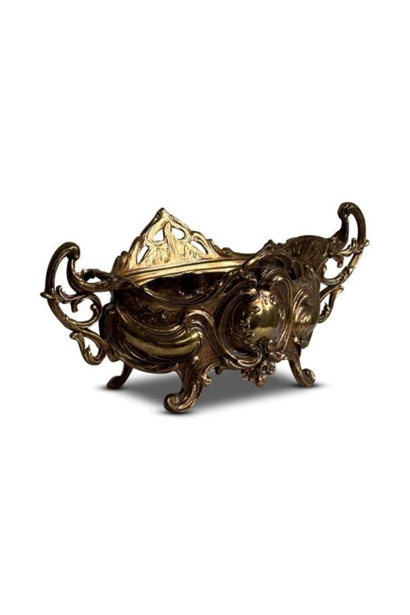 Questa ciotola con piedini rococò Jardiniere in ottone antico vanta dettagli ispirati al movimento Art Nouveau, che si è imposto tra la fine del XIX e l'inizio del XX secolo. Questo pezzo ornato è caratterizzato da una ciotola con piede rococò con