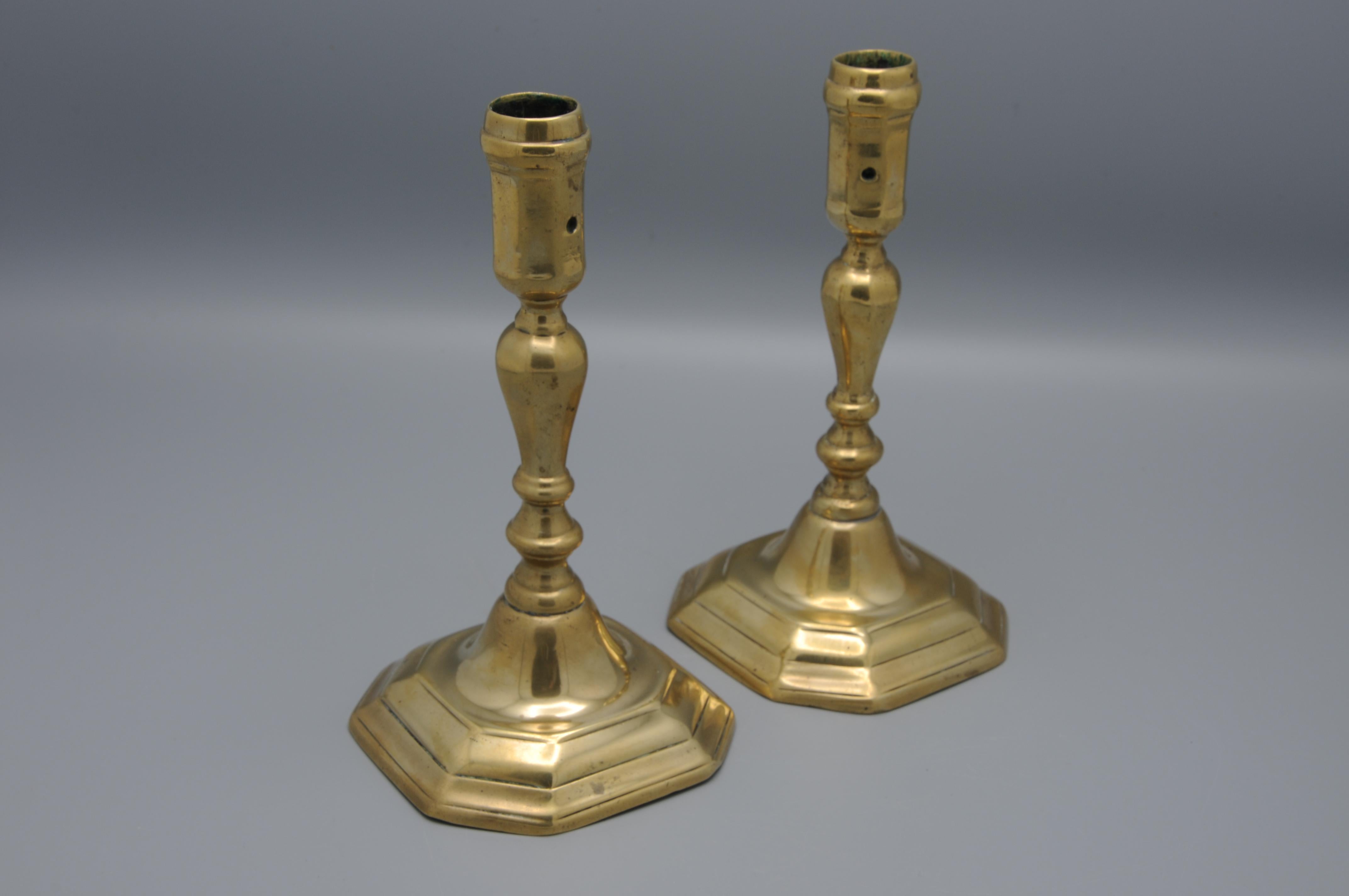 Candeleros de latón franco-flamencos, es decir, del periodo barroco holandés o francés del siglo XVIII. 
Cada una con una base octogonal que sostiene tallos balaustres y copas para velas. 
(Cada vaso de vela tiene un orificio para retirar la