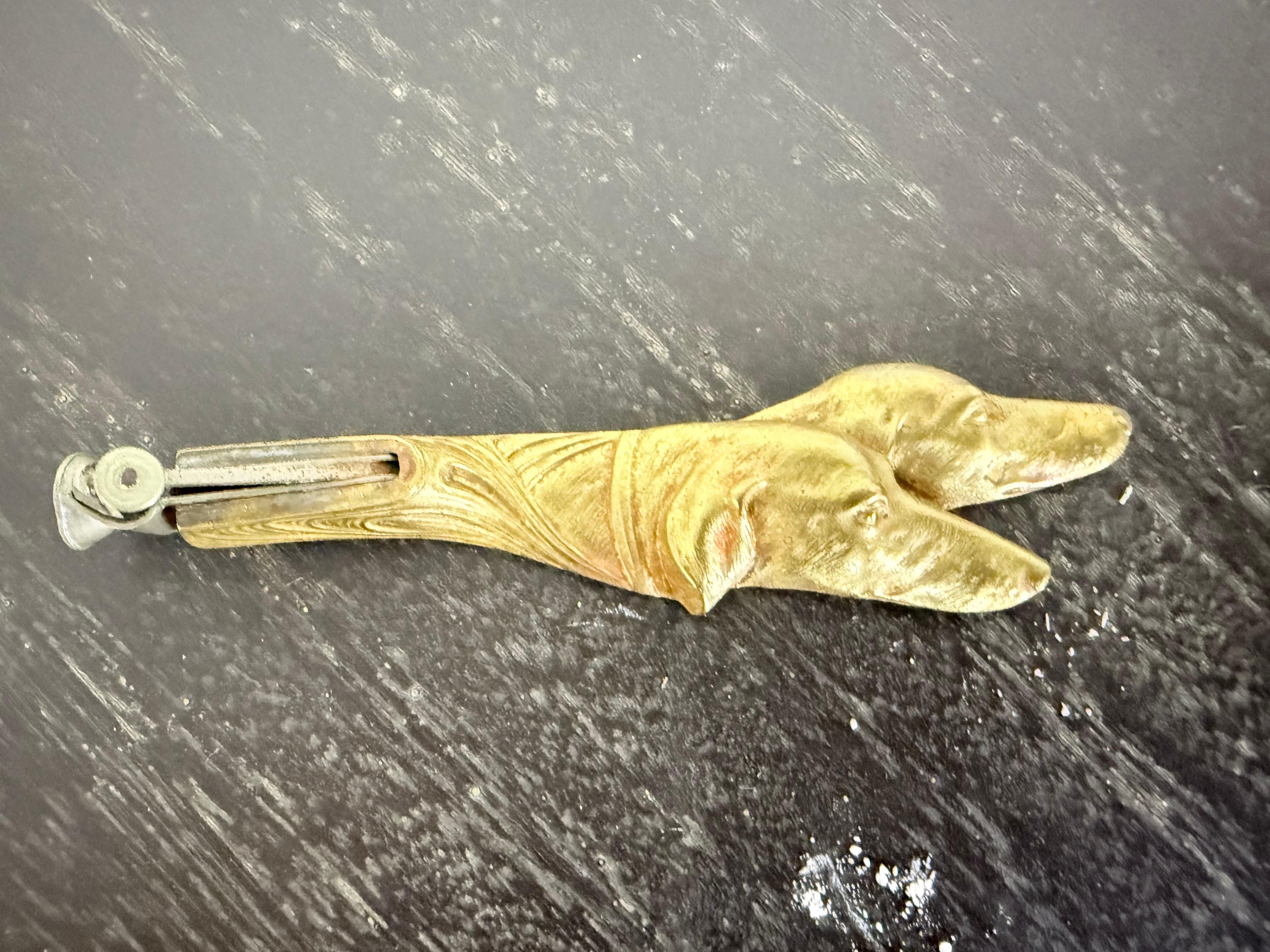 Cortapuros antiguo finamente fundido con un mango escultórico en forma de dos perros de caza, probablemente sabuesos o perros de muestra, representados con detalles realistas y rasgos expresivos. Fabricada en latón macizo, esta pieza data de finales