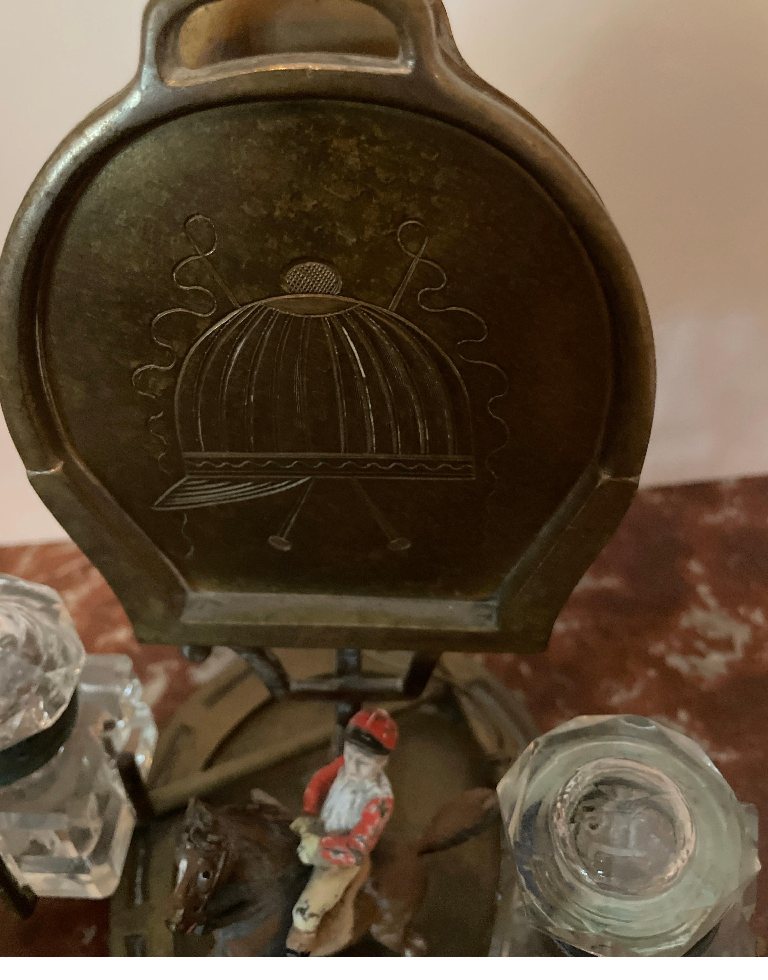 Antique Brass letter holder and inkwell. The base is a horseshoe with a horse & jockey attached. There is a cut glass crystal inkwell on each side. the letter holder is engraved with a rider's hat & flags. Great attention to detail.