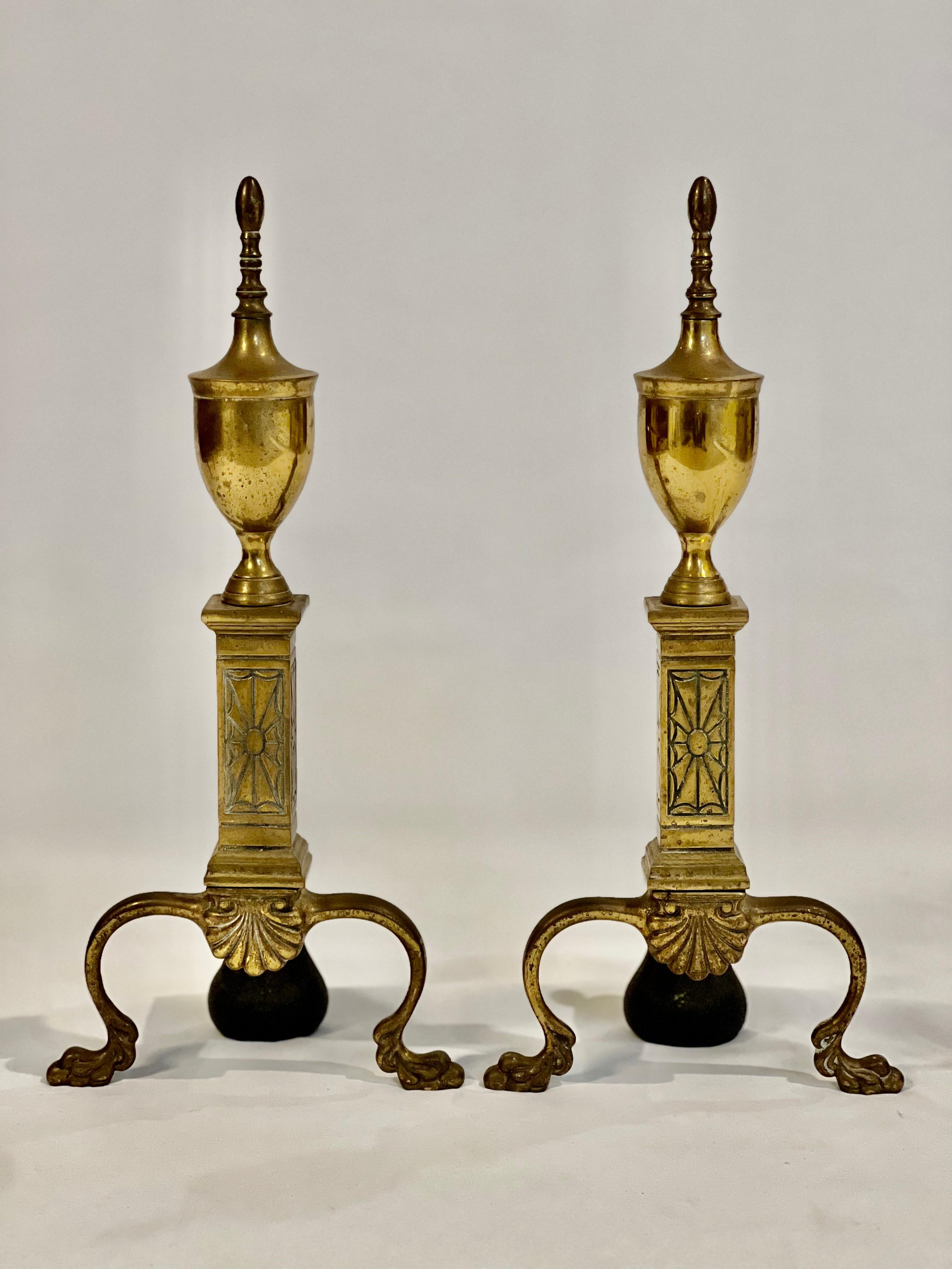 Antique brass andirons by Bennett Co., 1920's.

Elegant andirons Chippendale in style with a nod to Art Deco reflective of their period.  They feature a unique spider web design accompanied by a shell motif and classic paw feet.  They are supported