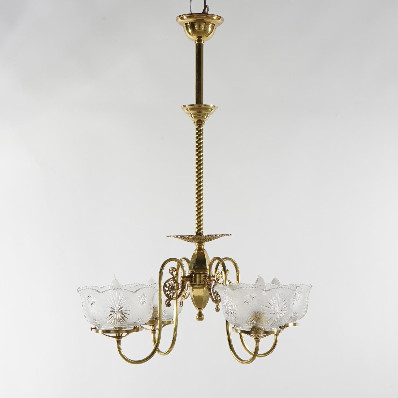 Ein antiker viktorianischer Kronleuchter bietet einen Messingrahmen mit vier spiralförmigen Armen, die in Leuchten mit Glasschirmen enden, um 1880

Maße - 31 