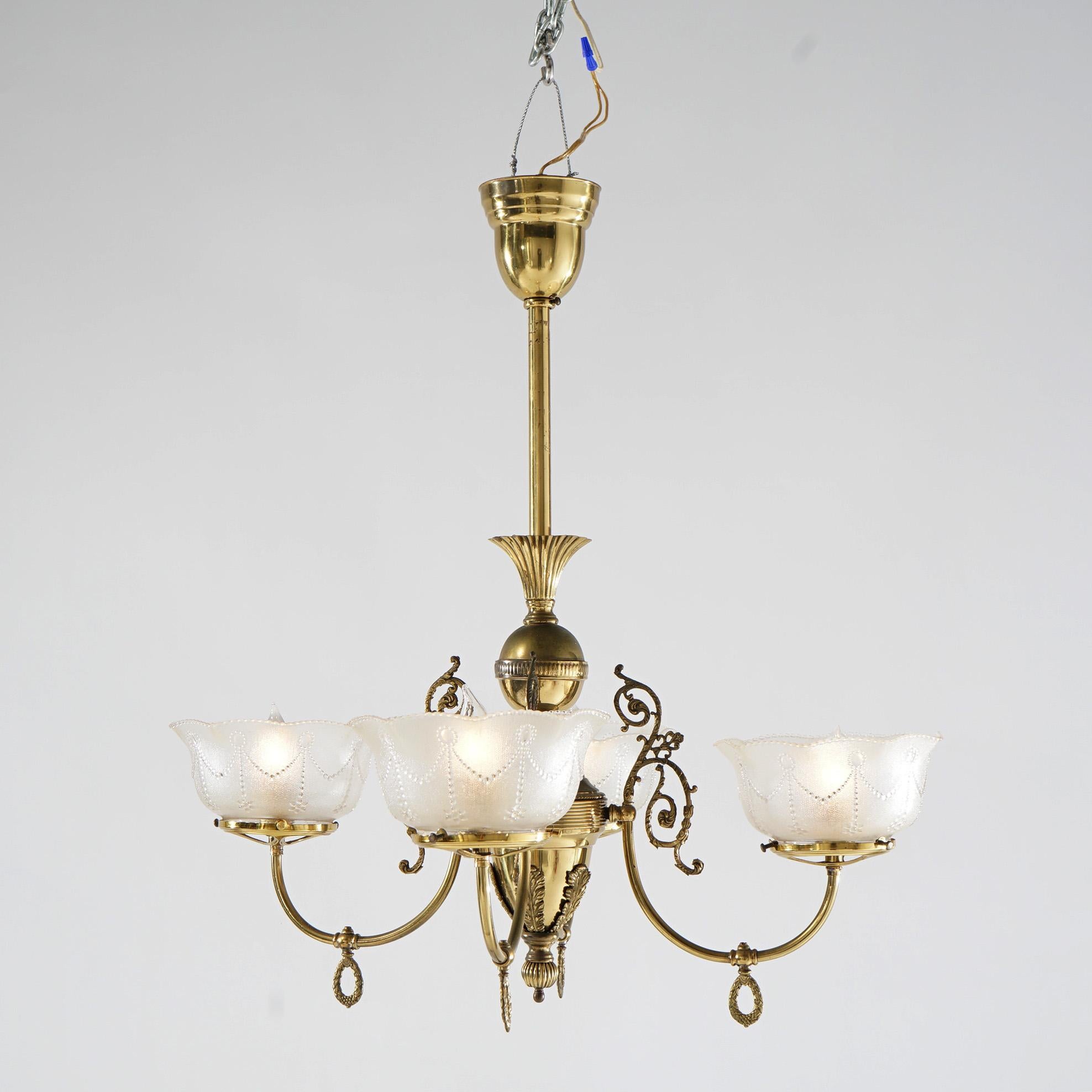 An antique gas chandelier offers brass frame in scroll and foliate form with four arms terminating in lights with glass shades, converted to electric, 19th century

Measures - 28