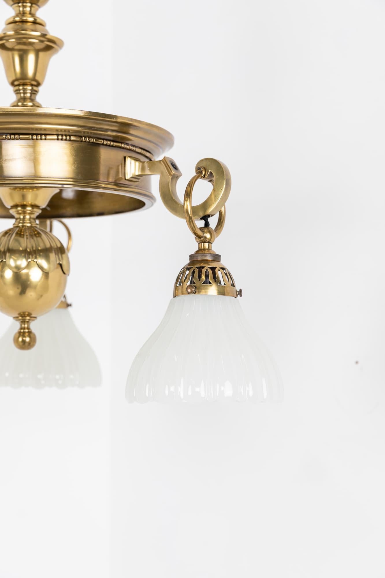 An incredibly elegant brass chandelier made in England by GEC - General Electric Company. c.1920

Heavy brass construction of a very high quality, complete with it's three perimiter pressed glass moonstone shades, ceiling loop and short length of