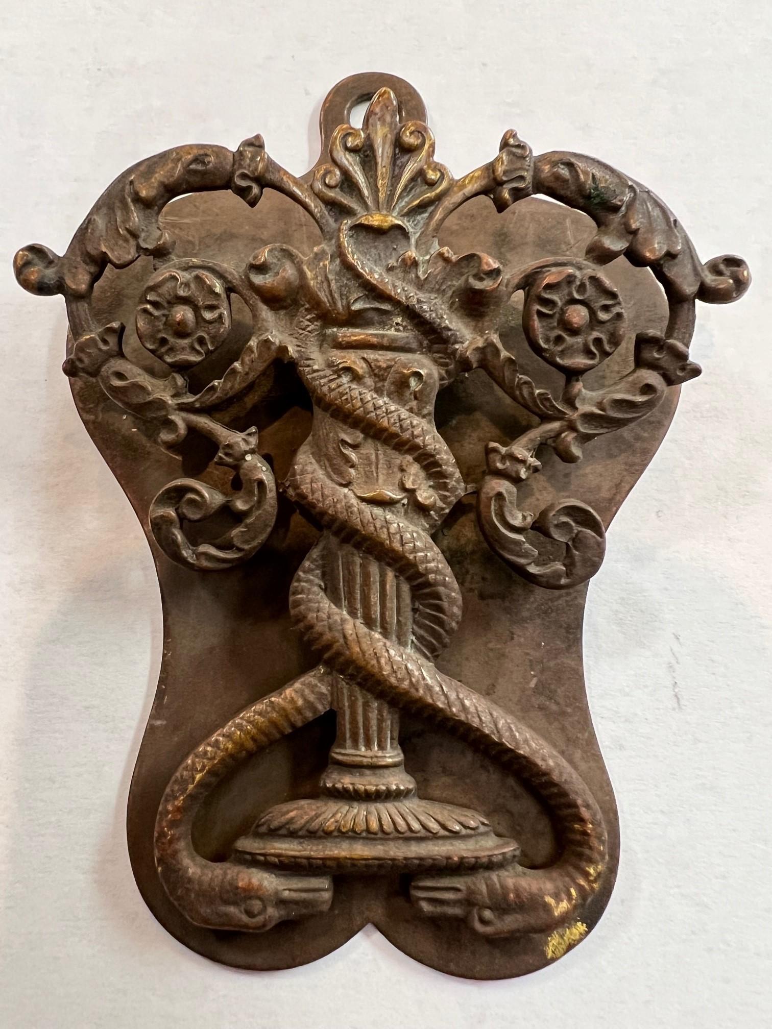 Antique brass letter or envelope holder with two snakes wrapped around a fountain, birdbath or column. Not sure the meaning of it, but it does make you think the symbol for medicine. Snakes are considered to represent healing and can be found