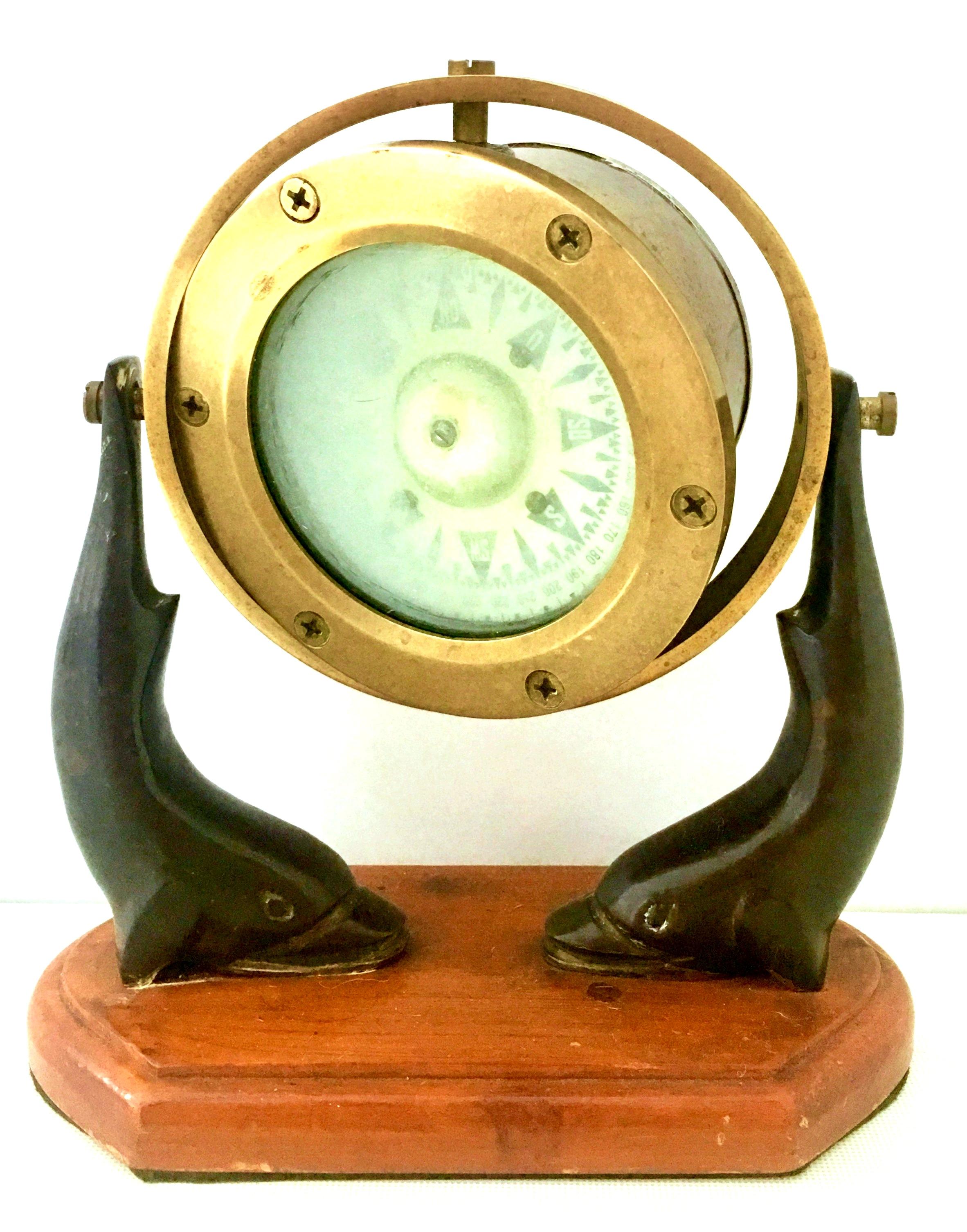 Early 20th century English working brass liquid ships compass. Mounted on a double bronze dolphin and pine wood articulating stand. 
Compass diameter, 4