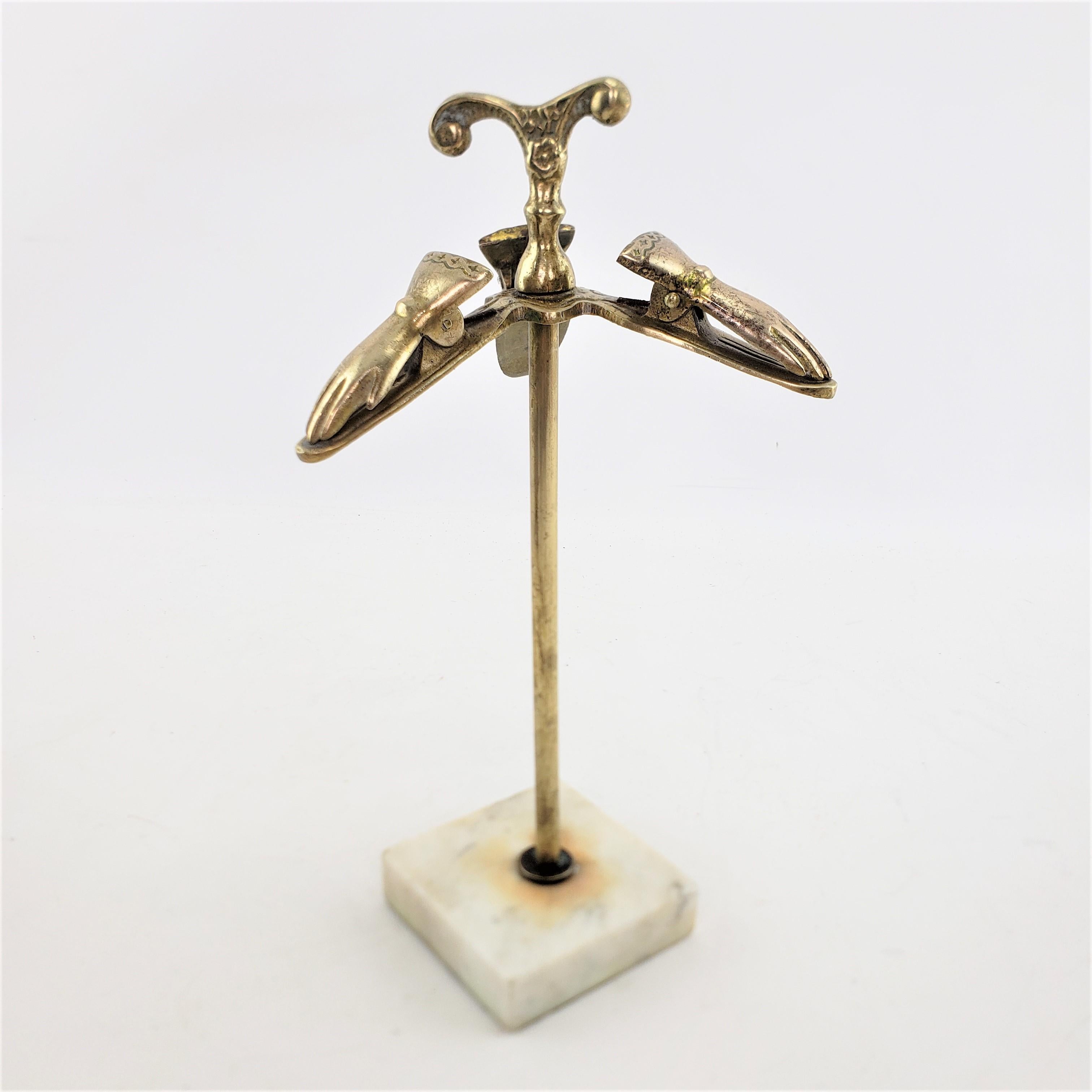 This antique brass and metal glove holder or stand is unsigned, but presumed to originate from England and date to approximately 1920 and done in a Victorian style. The stand is composed of brass and brass patinated metal and has a cast decorative