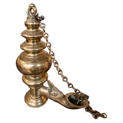 Lampe à huile en laiton vieilli, avec chaîne et éteignoir décoratif.