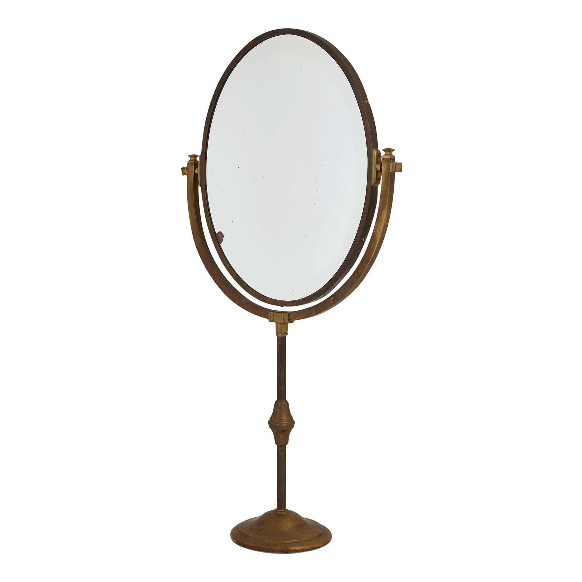 Antique brass oval table mirror
Continental, c. 1900
Measures: Height 86cm, width 46cm, depth 17cm

This fine table mirror is crafted from brass. The mirror is oval in shape and is set within a brass U bracket, which is raised atop a slender