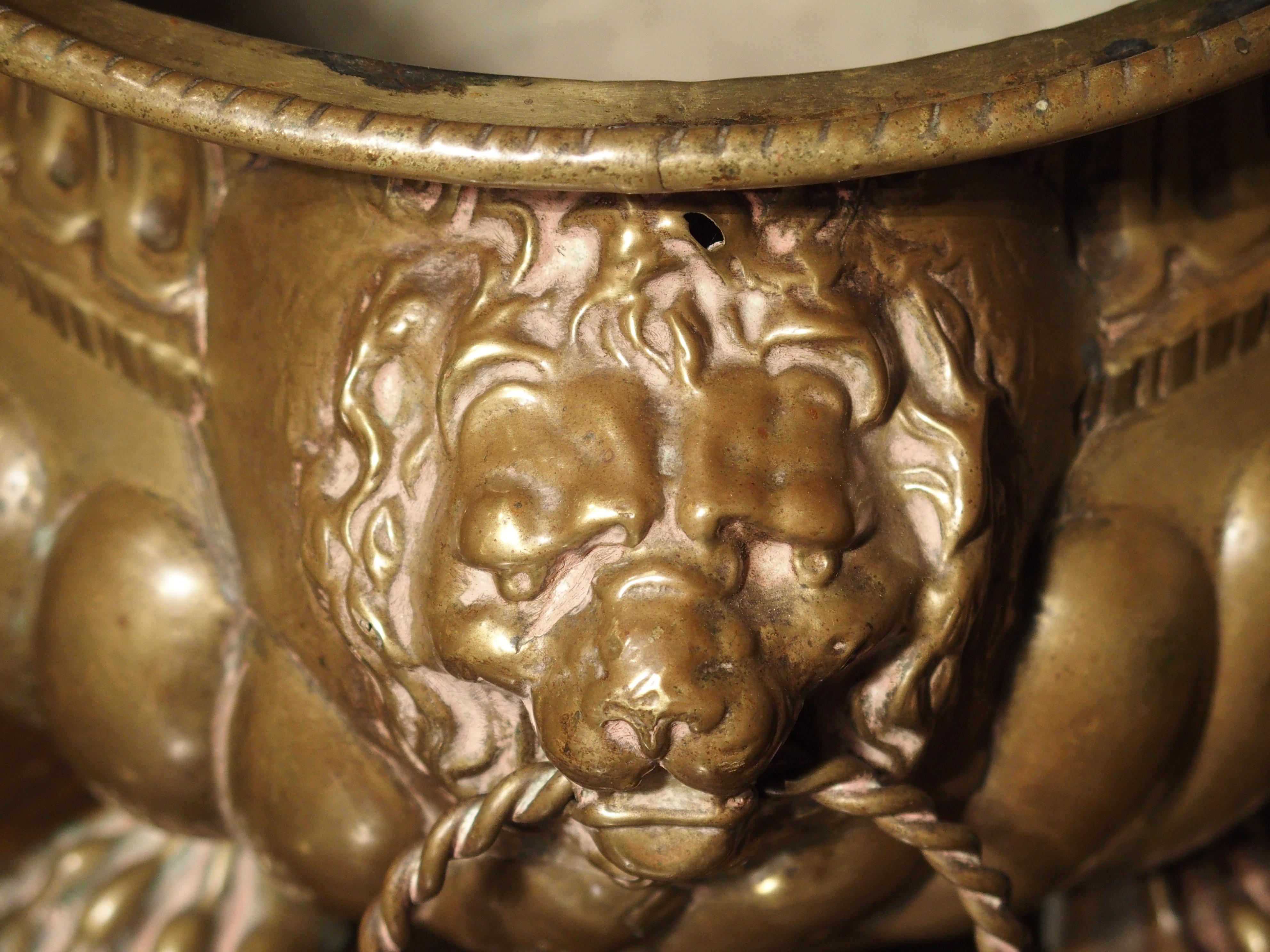 This large antique oval brass jardinière from France has wonderful lion heads motifs with rings in their mouths for the handles. The sides have gadrooned lobes under a band of linear scoop motifs. All this rests upon four lion’s paw motifs. Perfect
