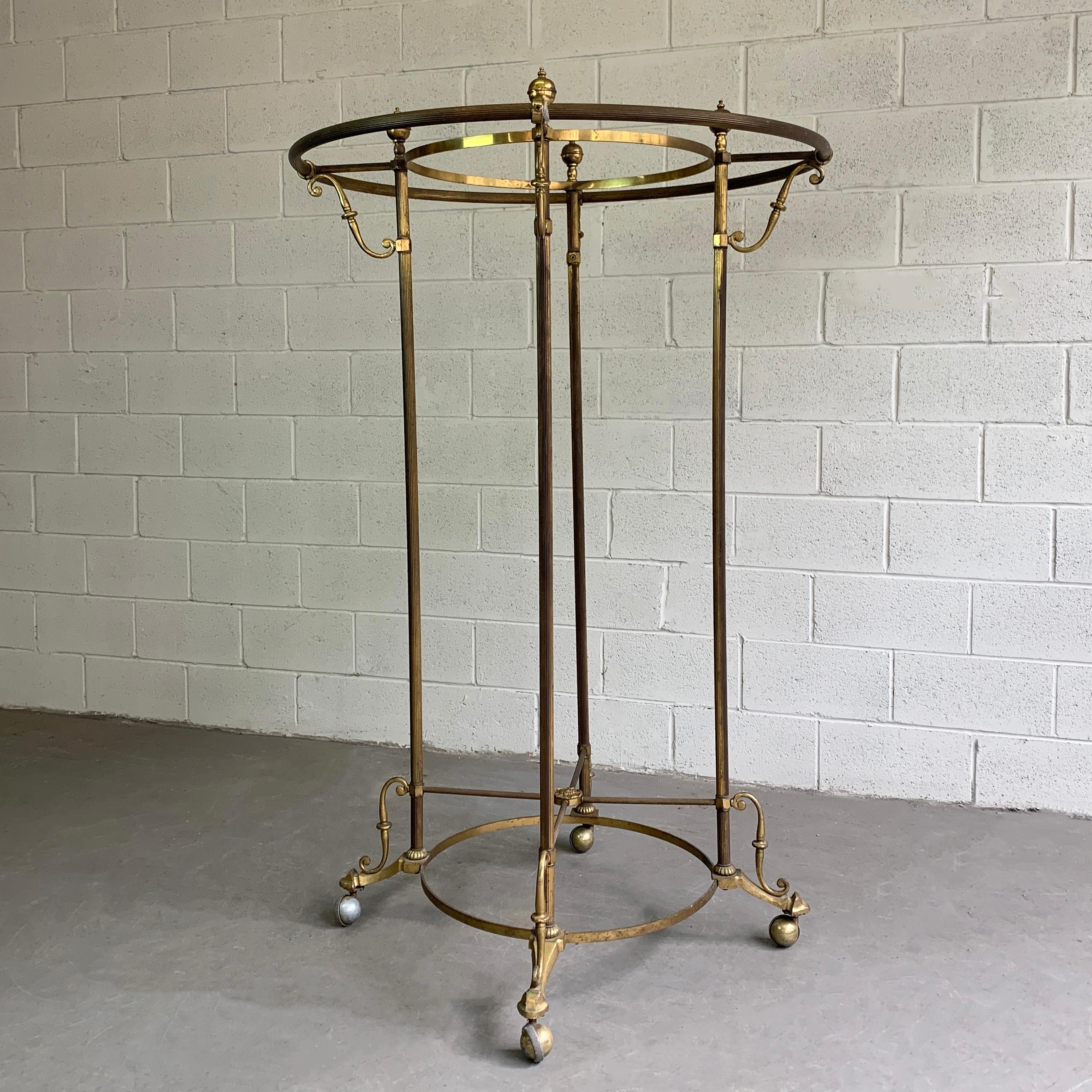 Antique, brass, rolling, rounder, garment rack fearures decorative touches. The 23.5 inch diameter inner ring can accept a glass top shelf.