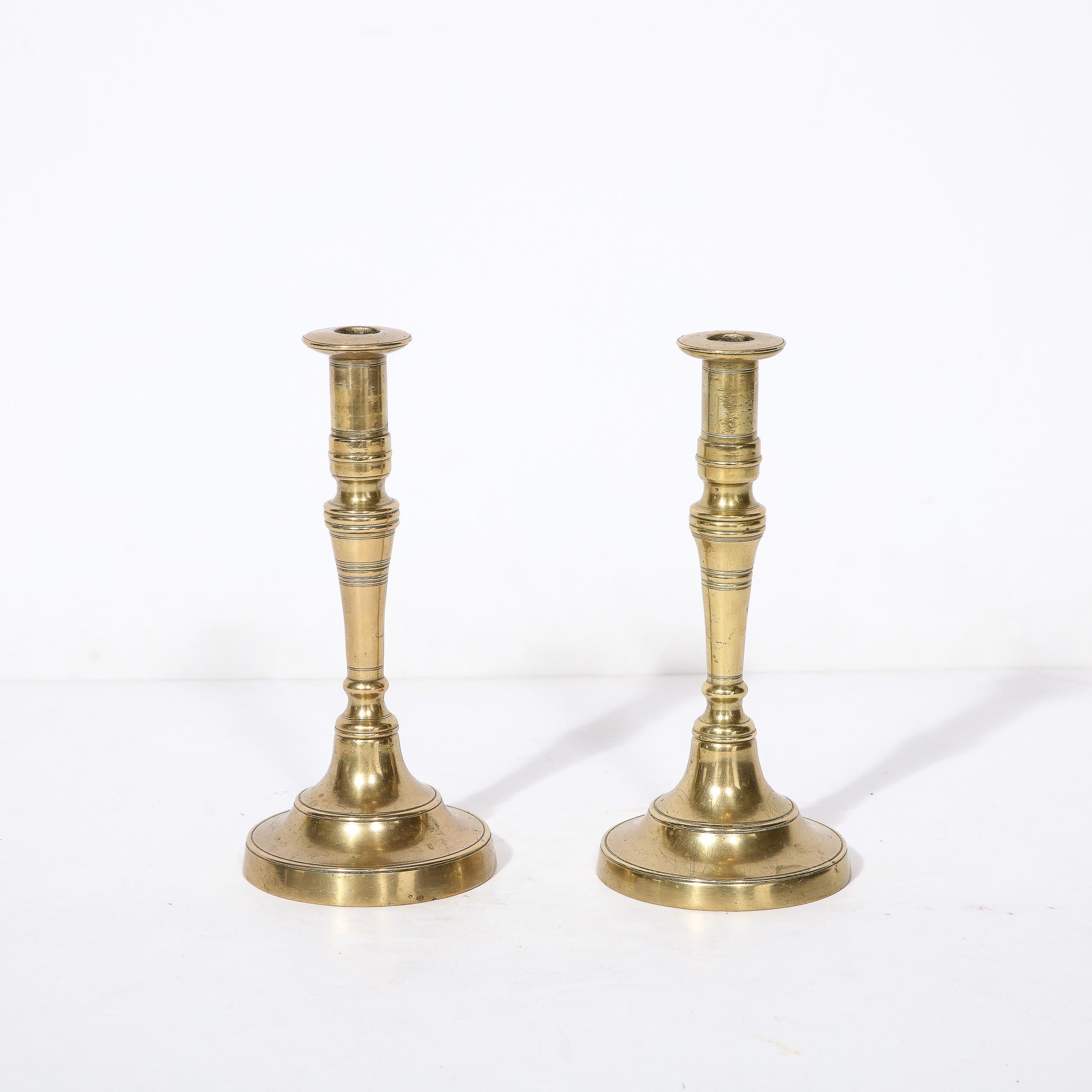 This Pair of Shabbas Candle Holders, rendered in hand wrought  brass with refined and classical banded detailing originate from the United States, Circa 1910. Designed to be lit prior to sunset to honor the coming Sabbath in Jewish life, the usage