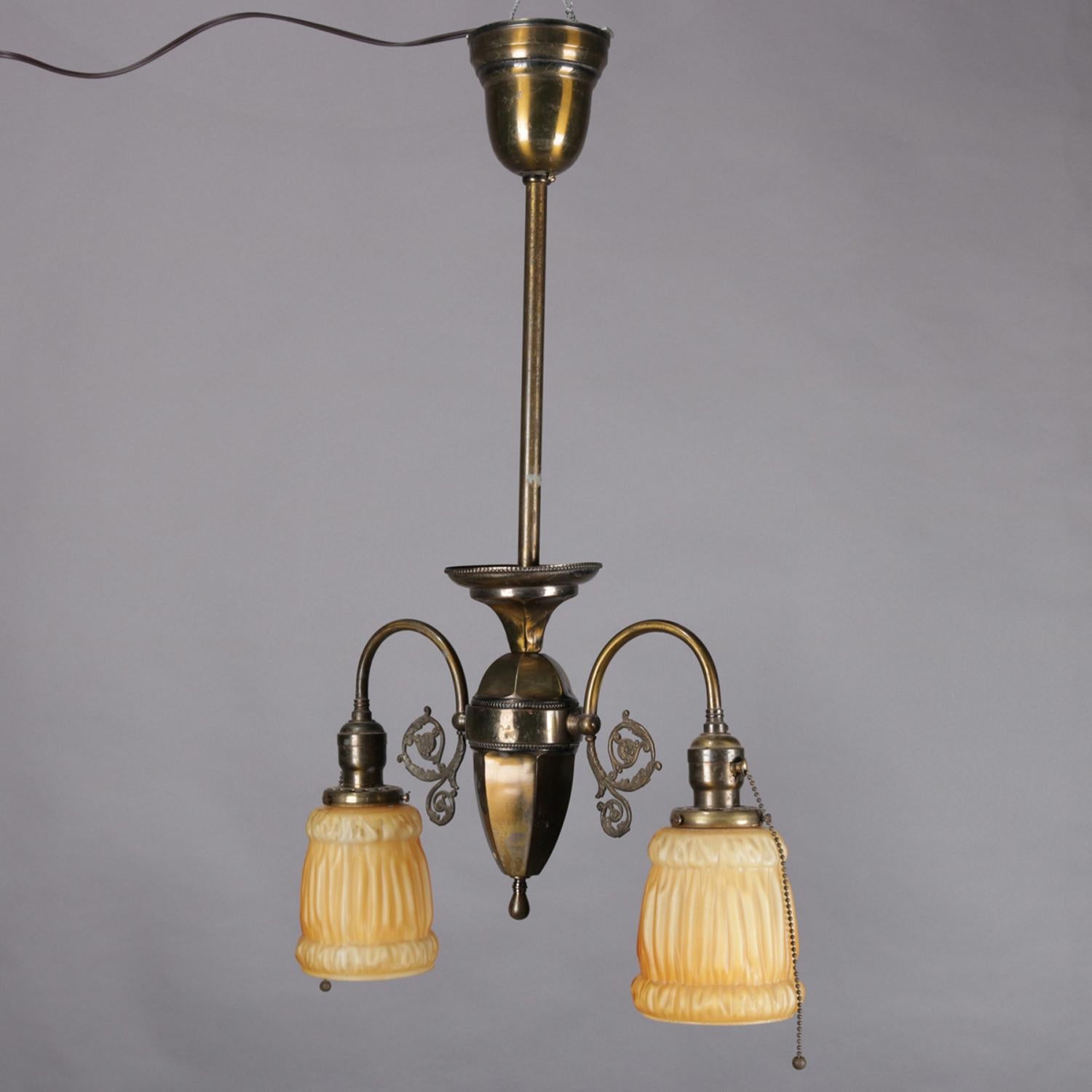 An antique drop light chandelier features brass frame with central faceted pendant having two scroll form arms terminating in lights with frosted glass shades, circa 1920

Measures: 27