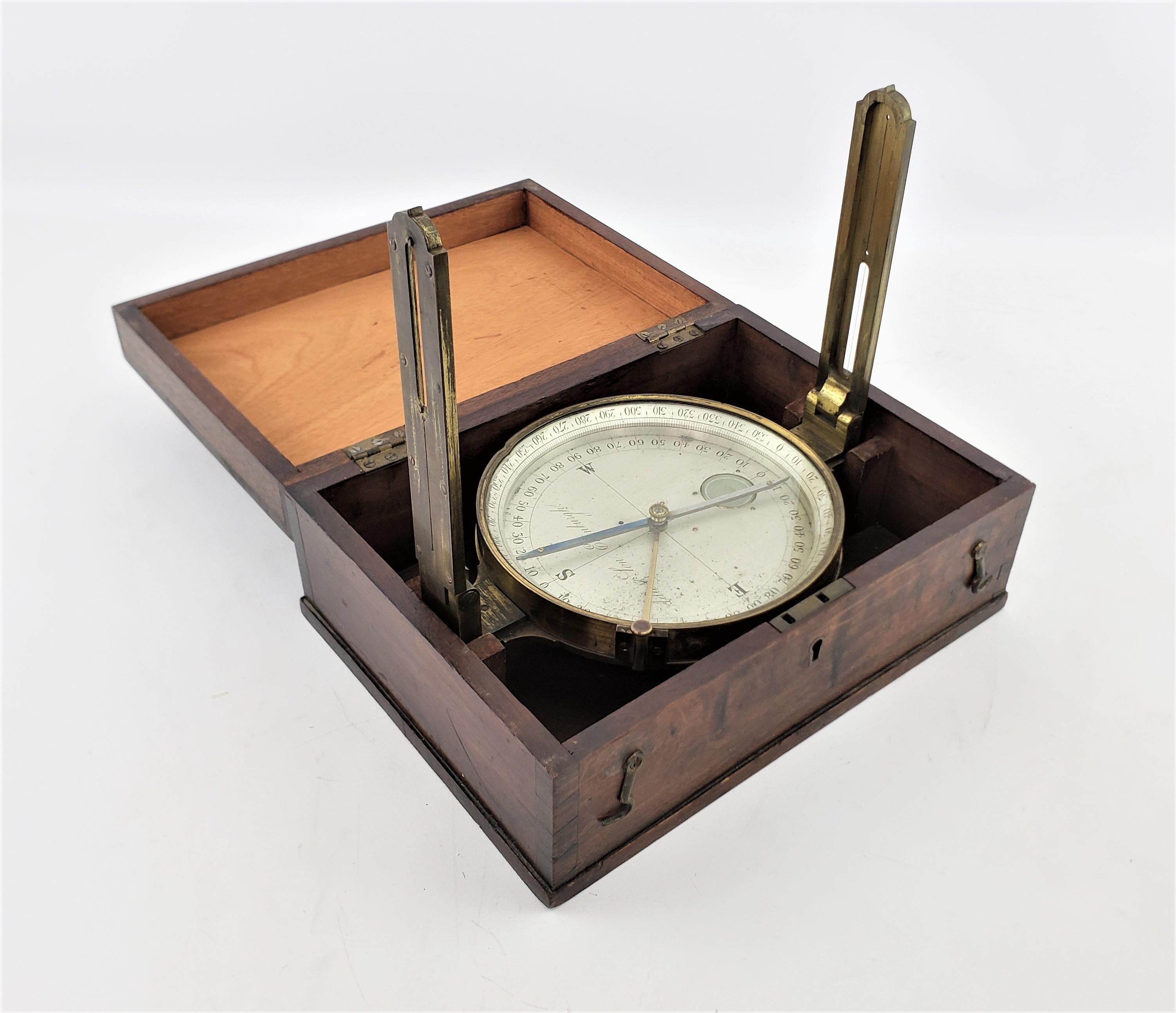 This antique surveyor's compass originates from Scotland and dates to approximately 1880 and made in the period Victorian style. The compass case is composed of solid brass with a metal face and hands. The compass has two hinged hangles that fold