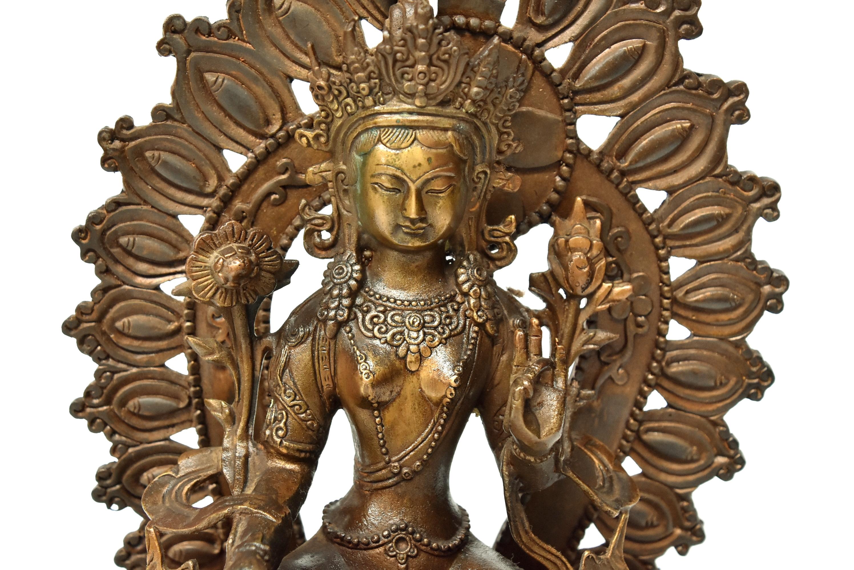 A beautiful antique brass Tibetan Green Tara. The Tara is seated on an elevated lotus throne, she wears a decorated crown and pearl lariats. She is surrounded by flowers and wrapped in a fluid sash. A removable back halo with fire pattern provides