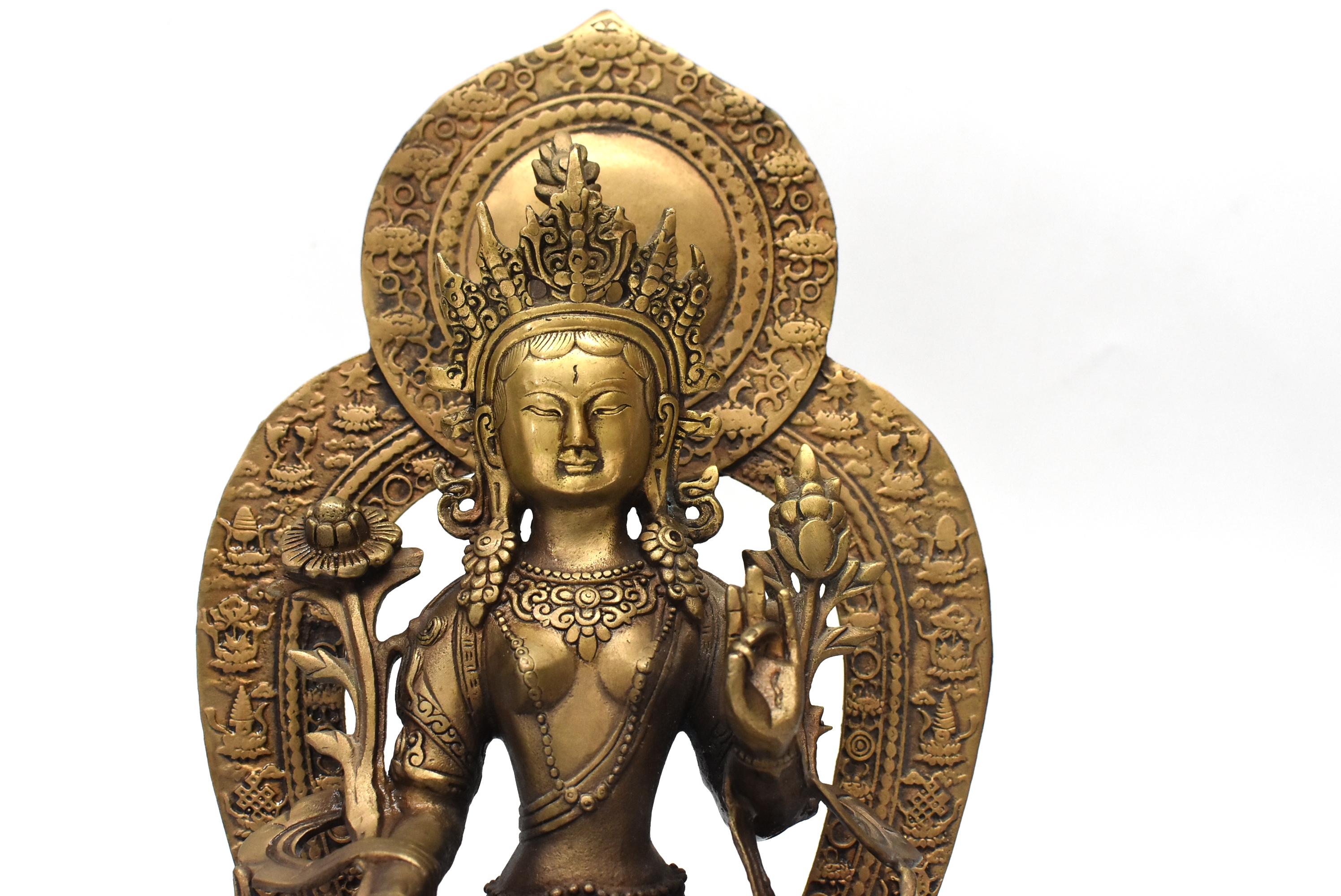 A beautiful, very substantial, antique brass Tibetan white Tara. The Tara is seated on an elevated lotus throne, she wears a decorated crown and pearl lariats, is surrounded by flowers and wrapped in a fluid sash. A removable back halo with embossed