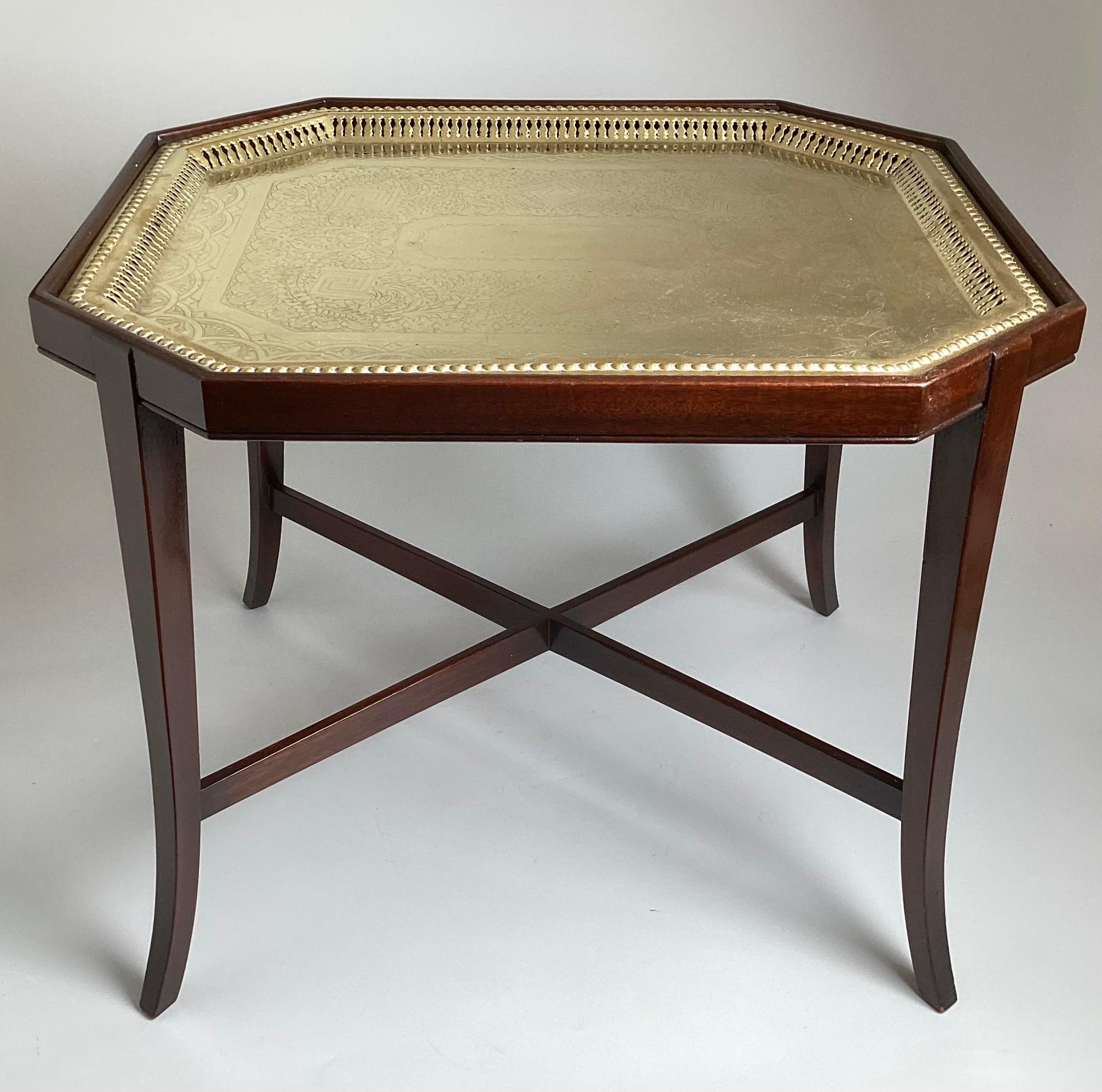 A charming polished brass 19th century tray with later custom mahogany base.  The tray with etched design, resting on a 1920's custom base with slim tapering flared legs and simple X stretcher base.  22.75 inches wide, 18 inches deep, 19 inches tall 