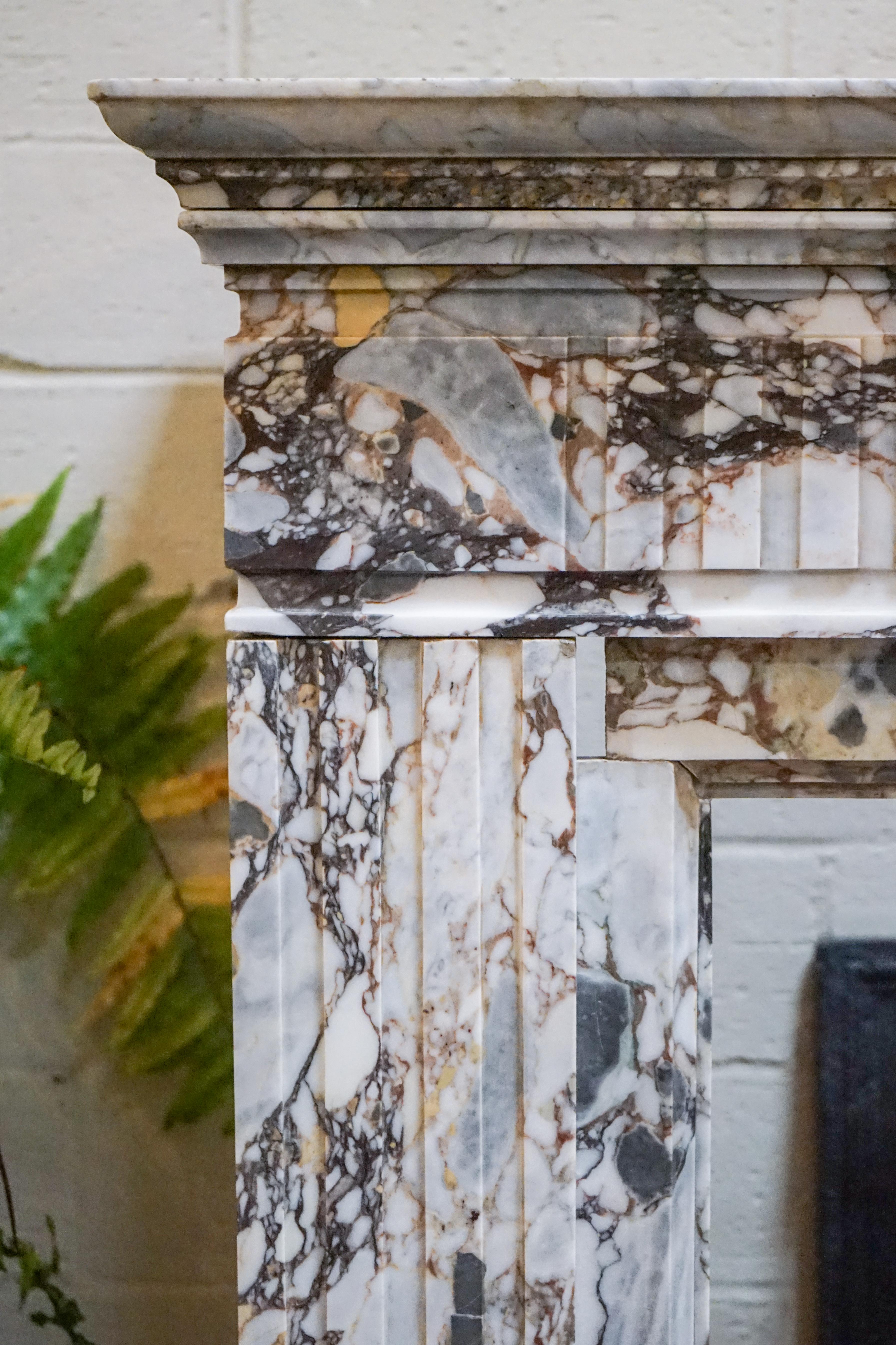 A Breccia Capaira marble fireplace is carved in the style of Louis XVI. 

Measurements:

Width = 63''
Height = 48.5''
Depth = 22.75''.