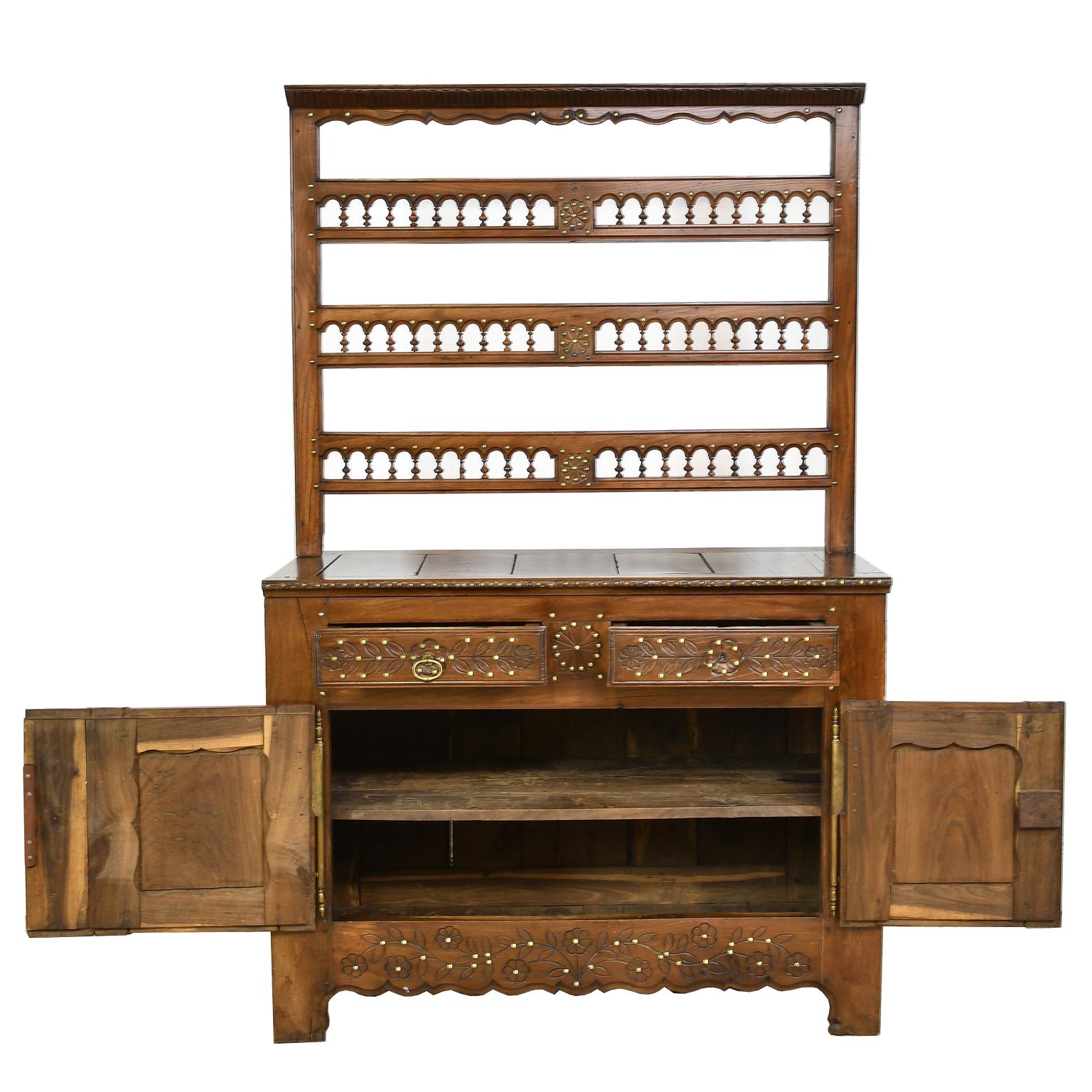 A lovely French Breton buffet-vaisselier or cupboard in chestnut with open dish rack. Incised foliate and floral carvings throughout are studded with decorative brass nailheads. Top is composed of an open rack with palmette carvings along crown