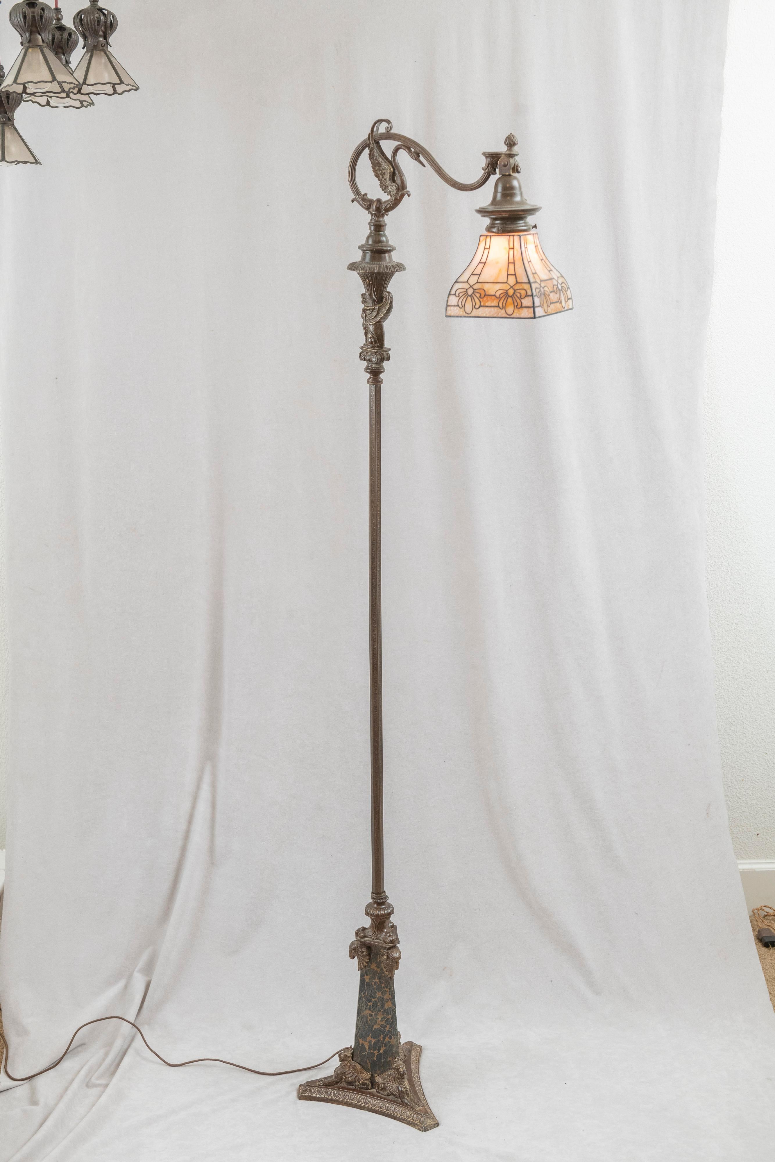  This incredible floor lamp has so many areas of interest that make it so special. The base, which we believe was done by Bradley & Hubbard, detailed castings of several characters. At the bottom there are 3 winged lions moving up to the top of that