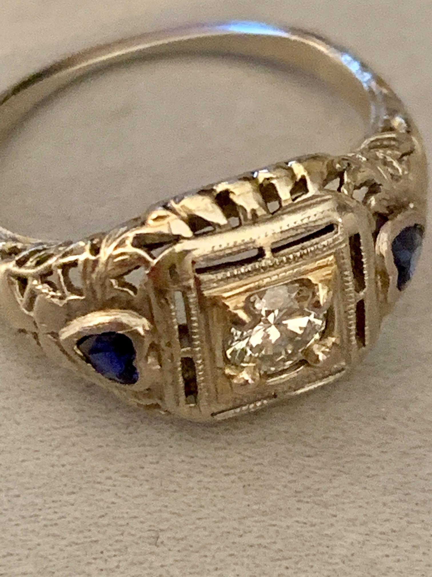 This lovely antique 18 karat white Gold ring features a 4mm brilliant cut Diamond of approximately .25 carats.  The average grade is Y-VS.  There are also two 2.7mm blue heart lab Sapphires.  

Size: 4
Weight: 2.2 grams